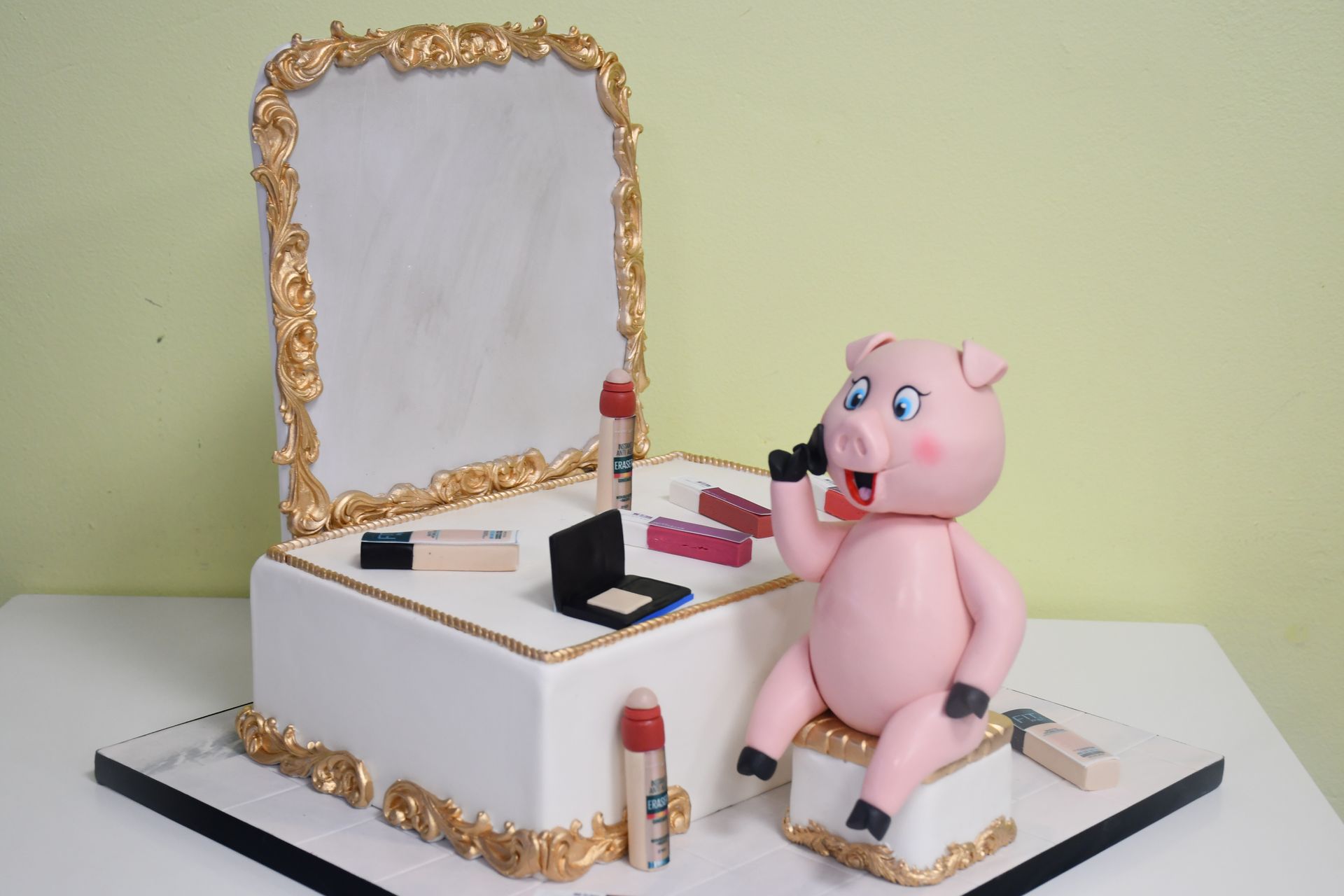 A cake with a pig sitting on top of it doing their makeup