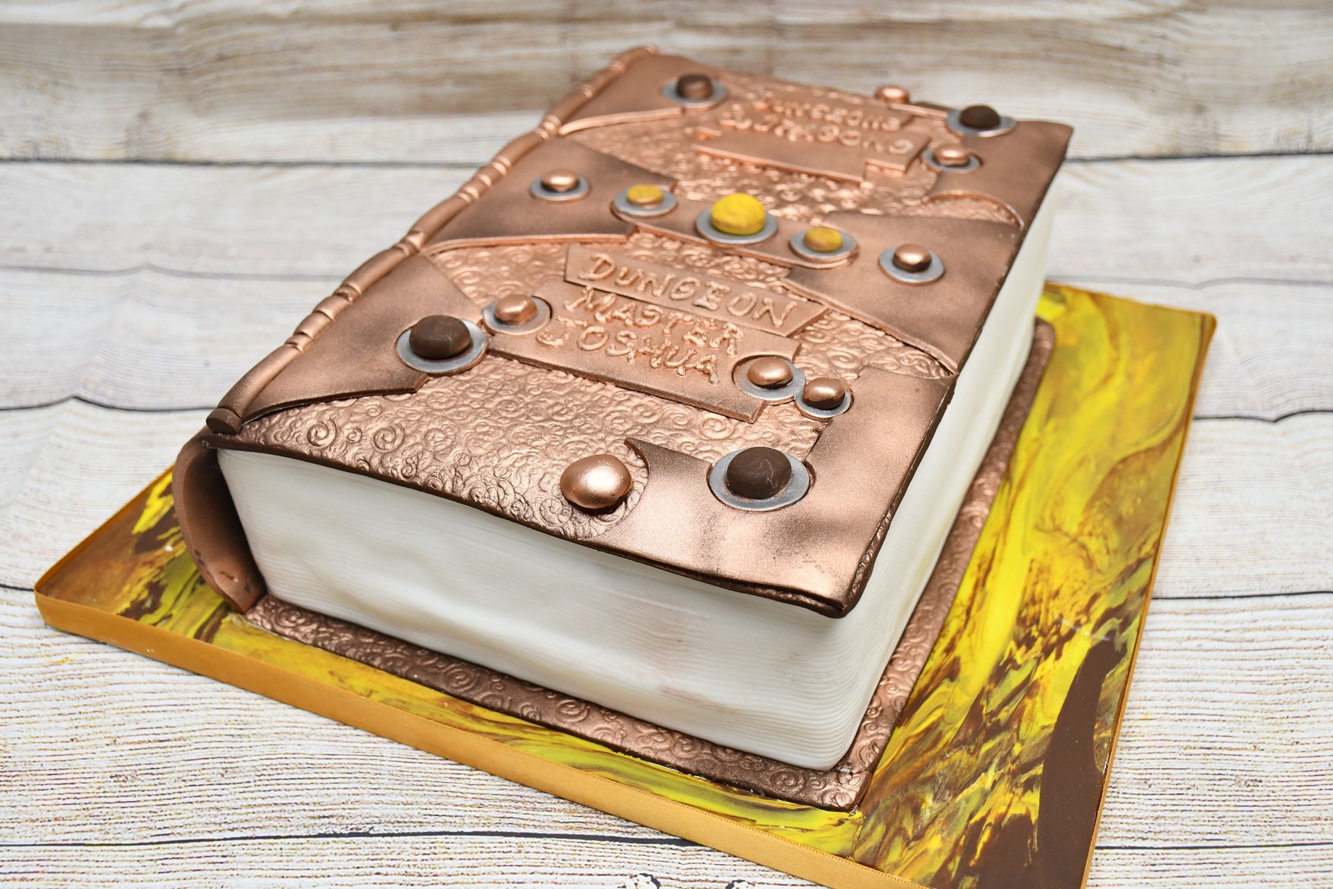A cake in the shape of a book is sitting on a wooden table.