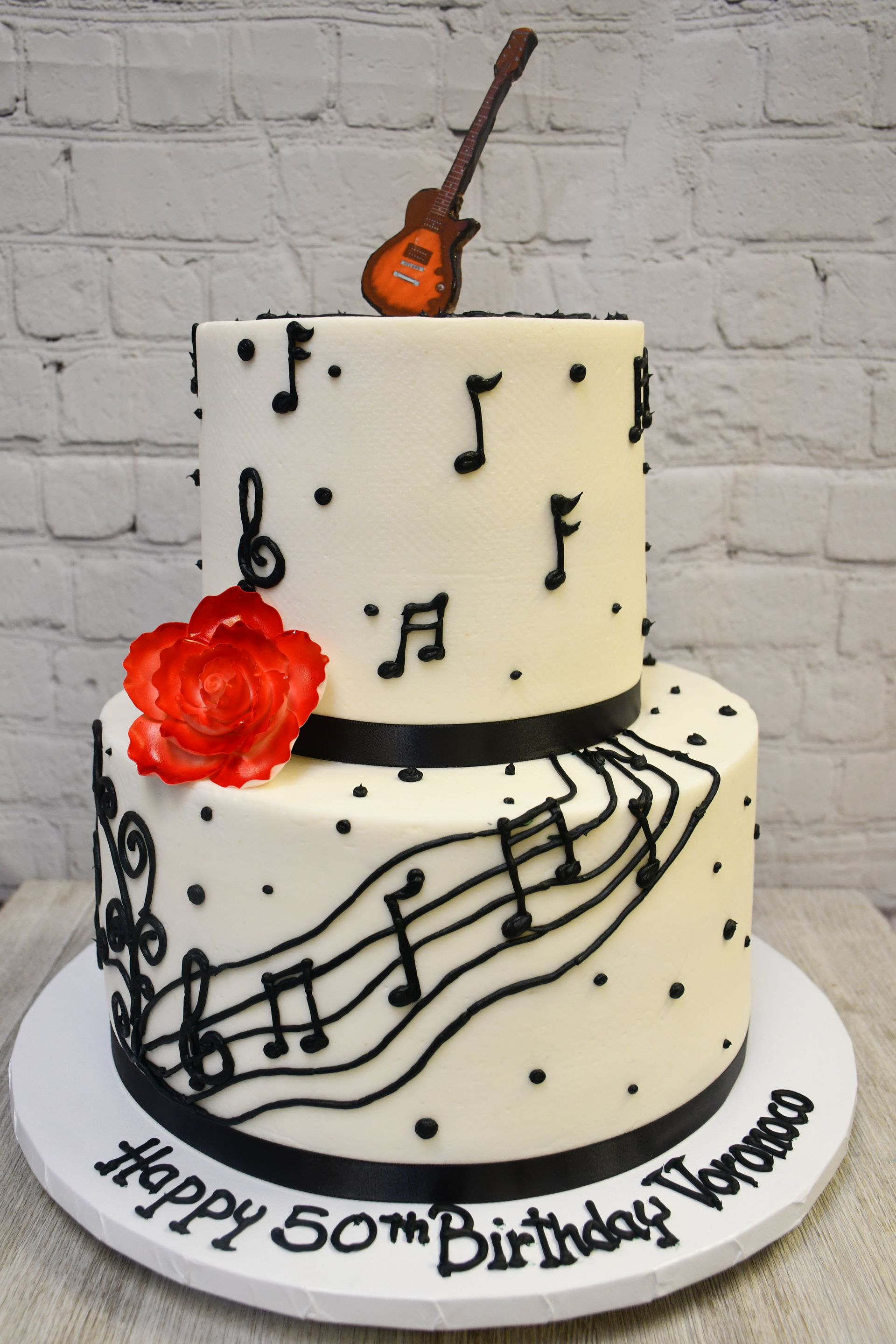 A birthday cake with music notes and a guitar on top