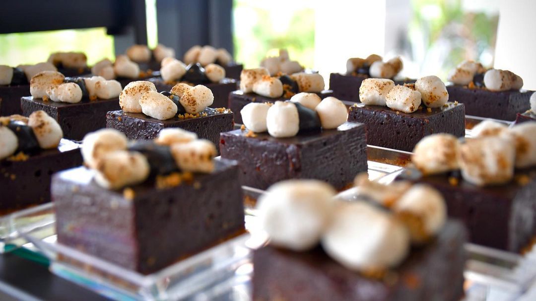 A close up of a tray of brownies with marshmallows on top.