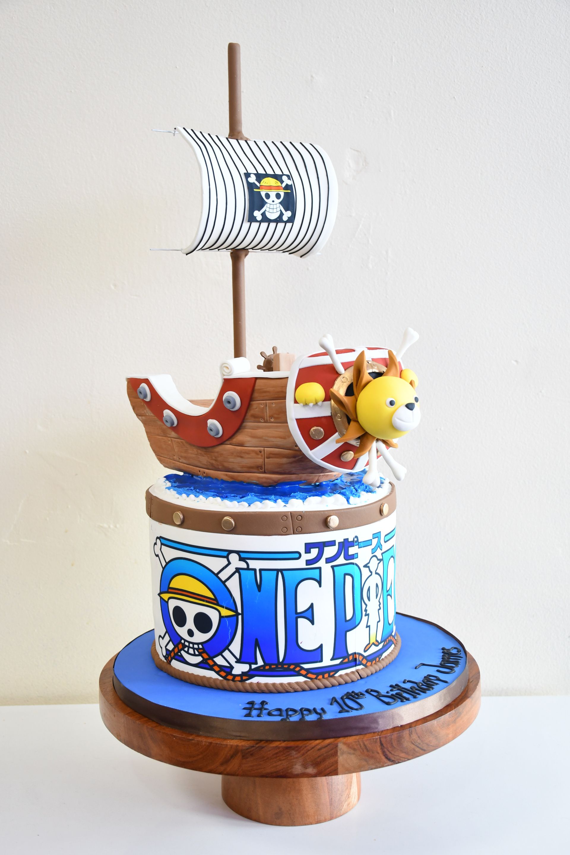 A cake with a ship on top of it and the word one piece on it.