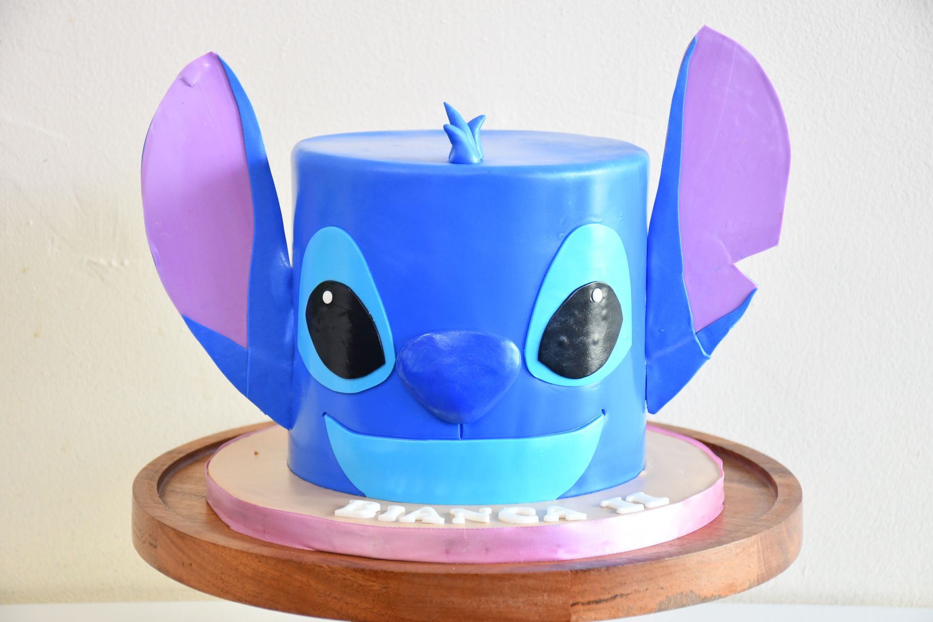A blue and purple cake with stitch 's face on it