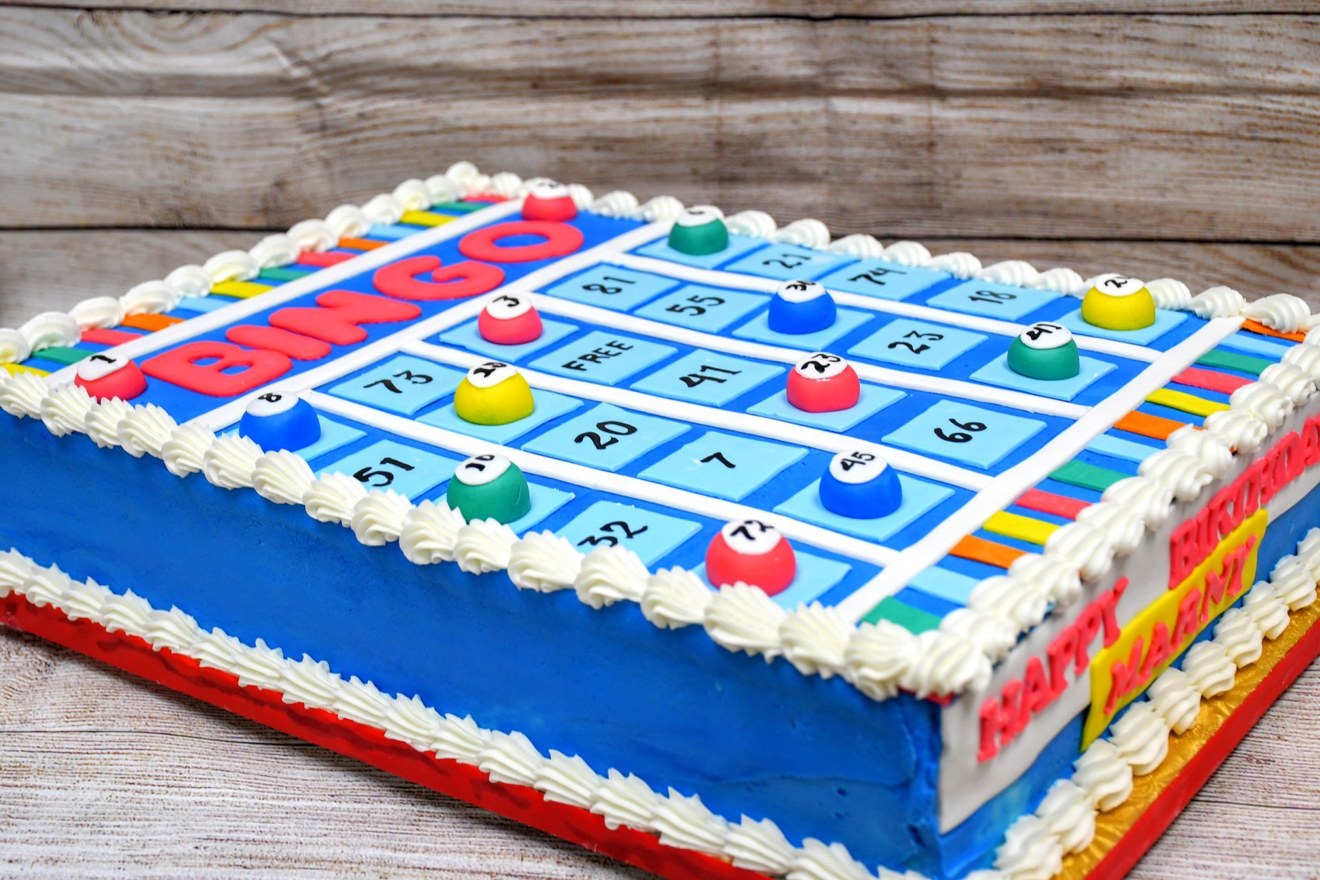 A cake decorated to look like a bingo board is sitting on a wooden table.
