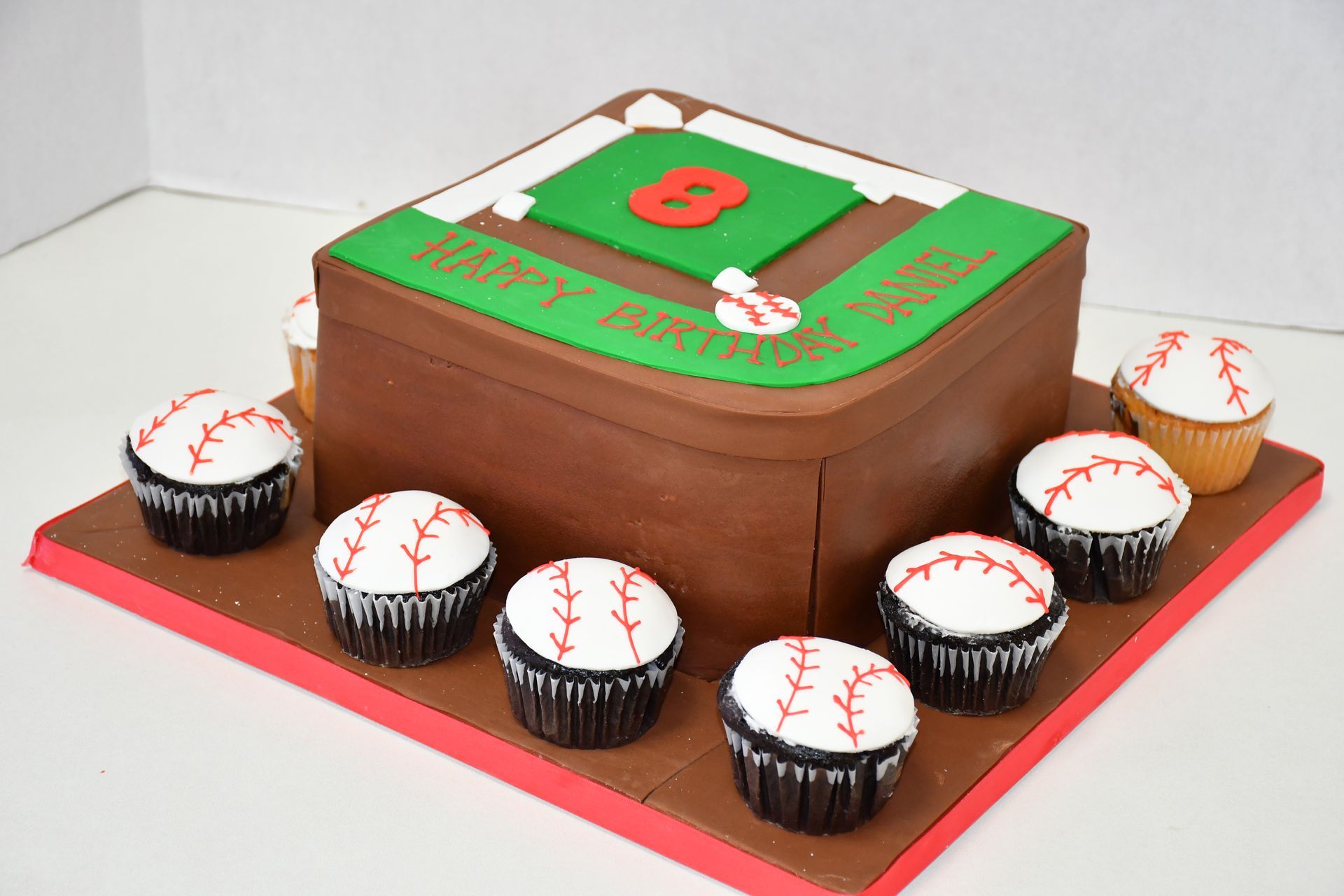 A birthday cake shaped like a baseball field with the number 8 on it