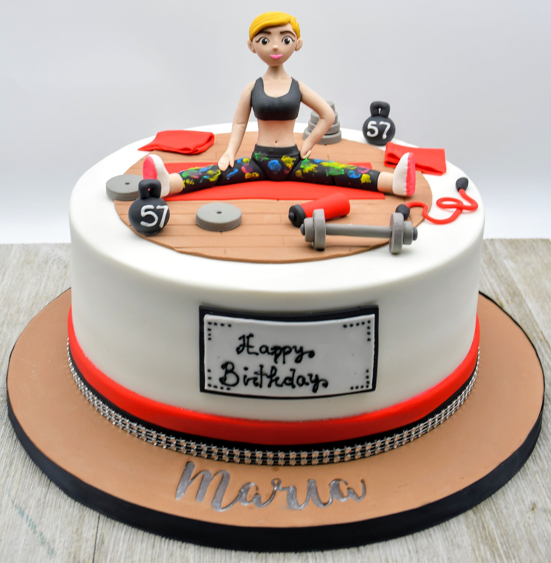 A birthday cake with a woman doing splits on top