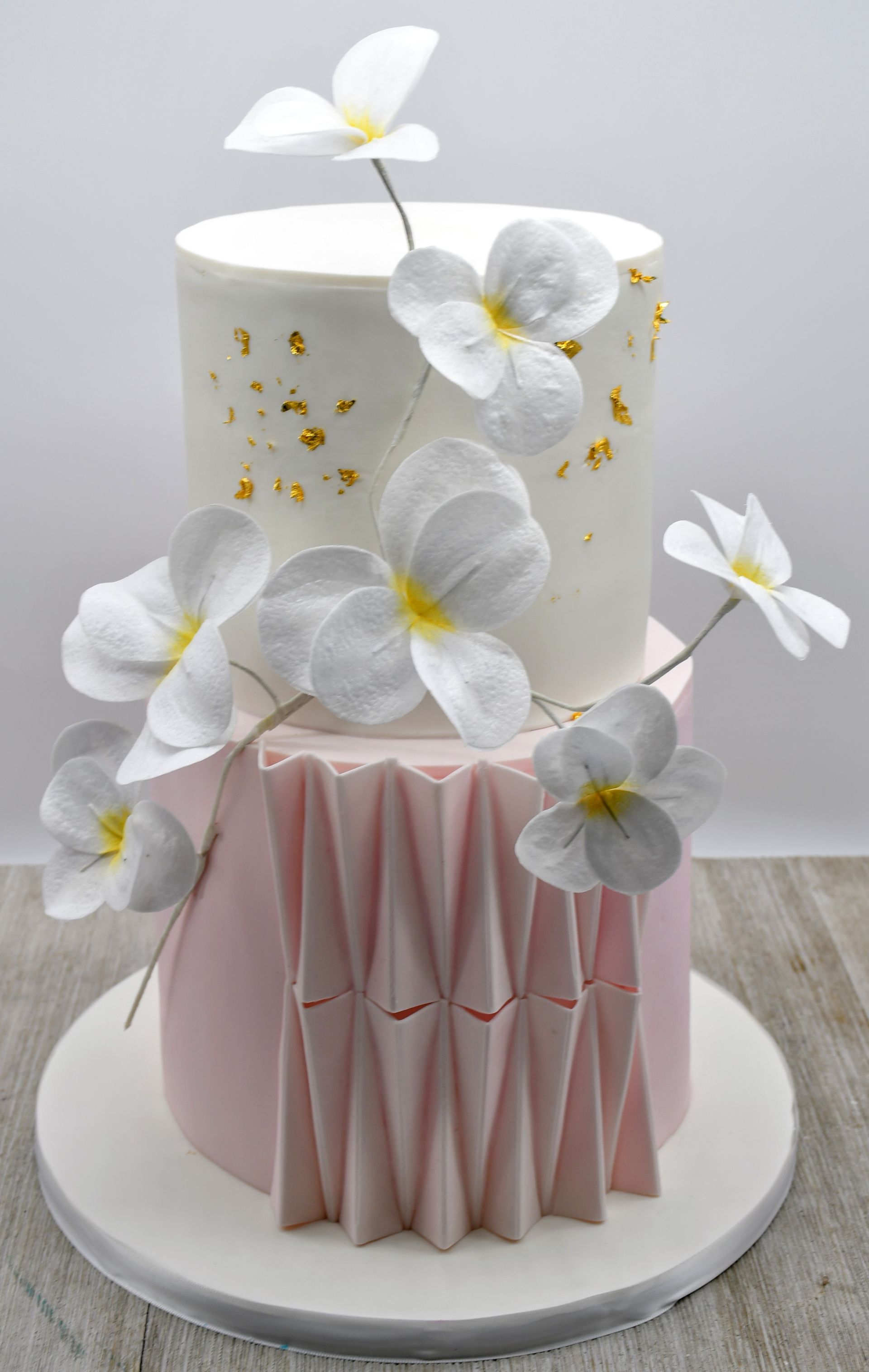 A white and pink cake with white flowers on top of it.