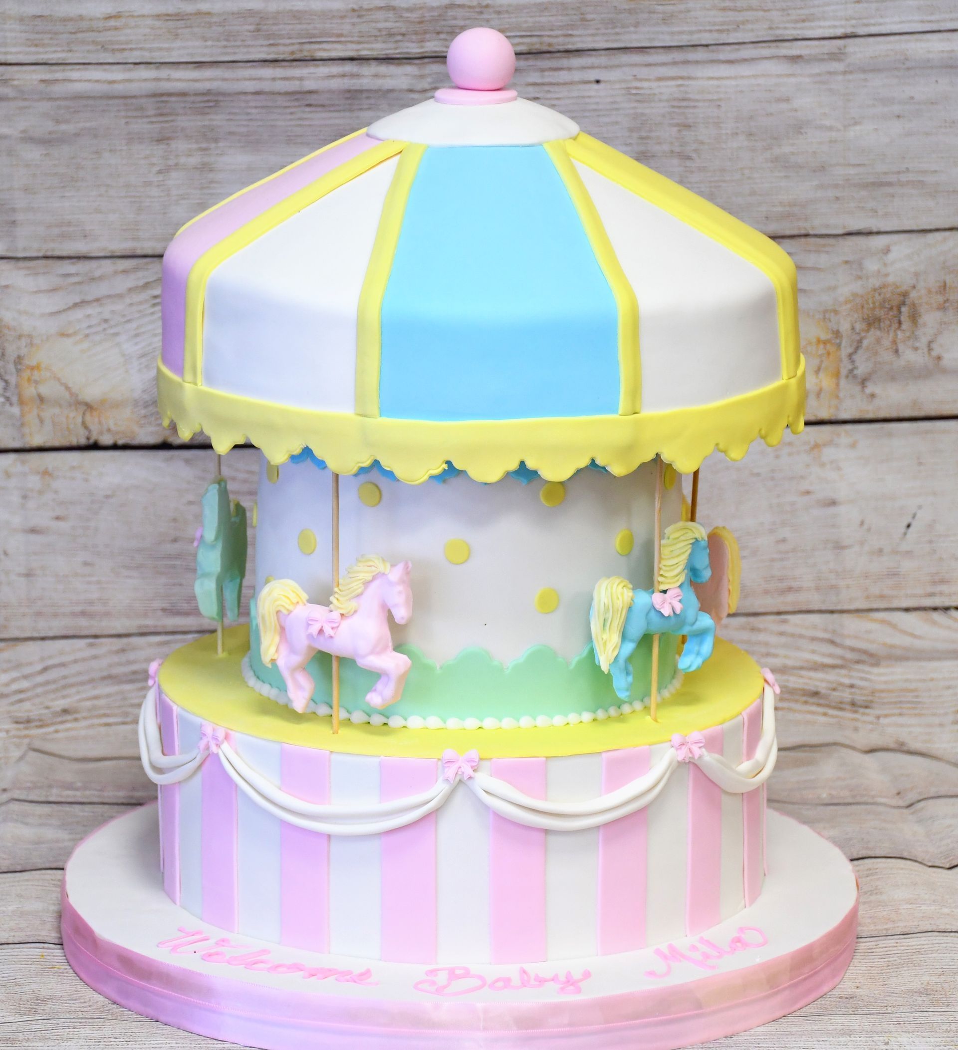 A cake that looks like a merry go round with horses on it