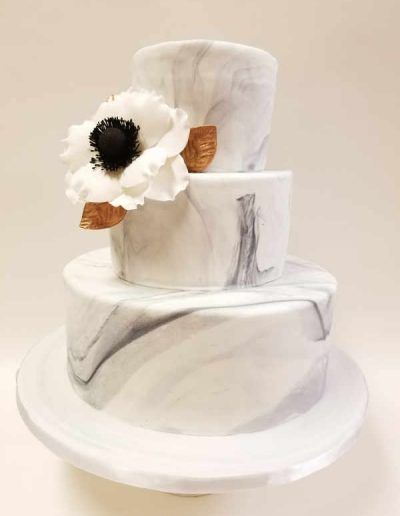 A white marble cake with a white flower on top.