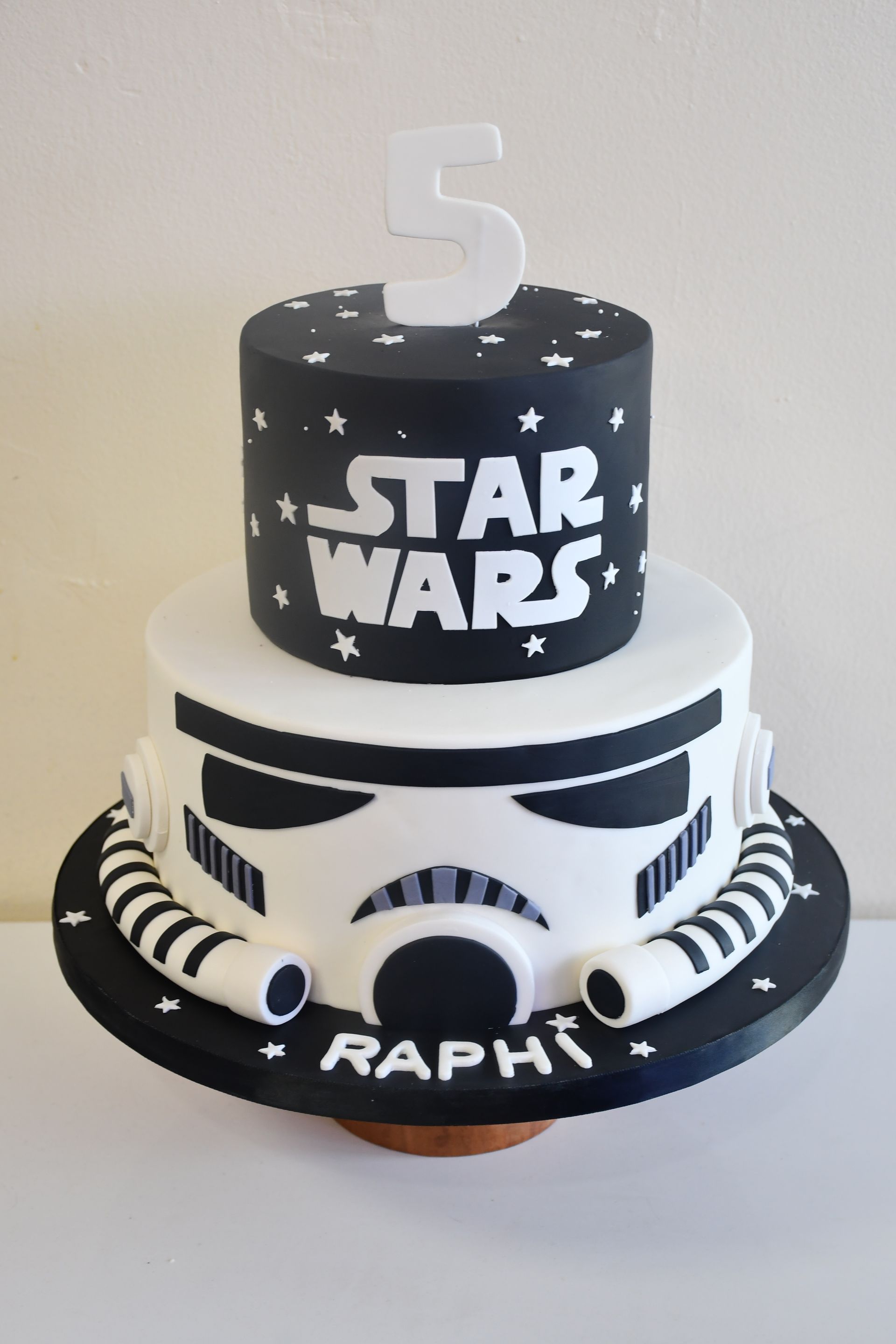 A black and white star wars cake with a stormtrooper on top.