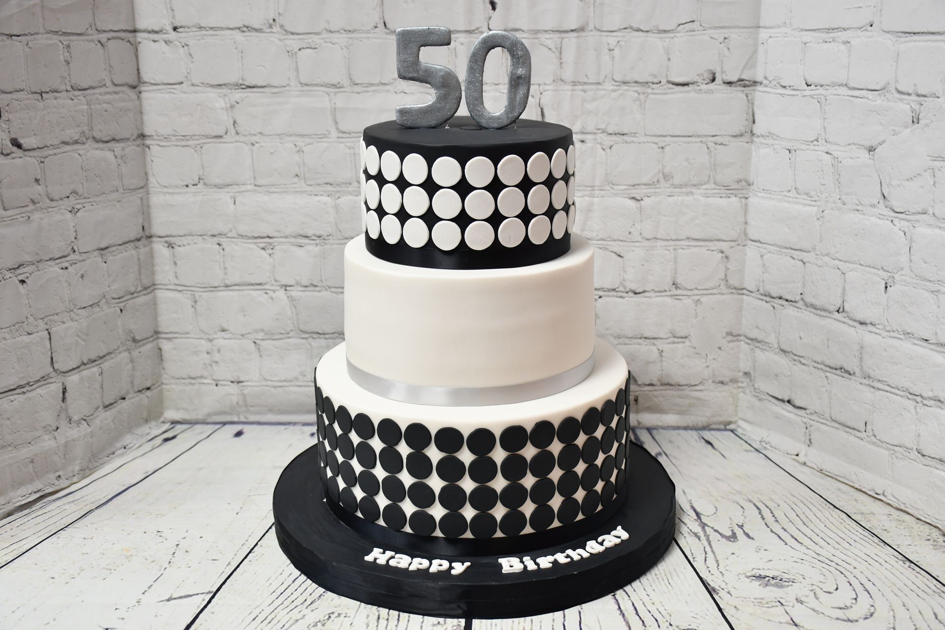 A black and white birthday cake with the number 50 on top