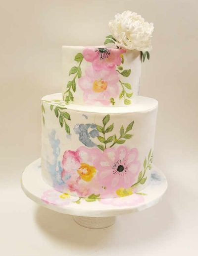 A cake with flowers painted on it is on a cake stand.