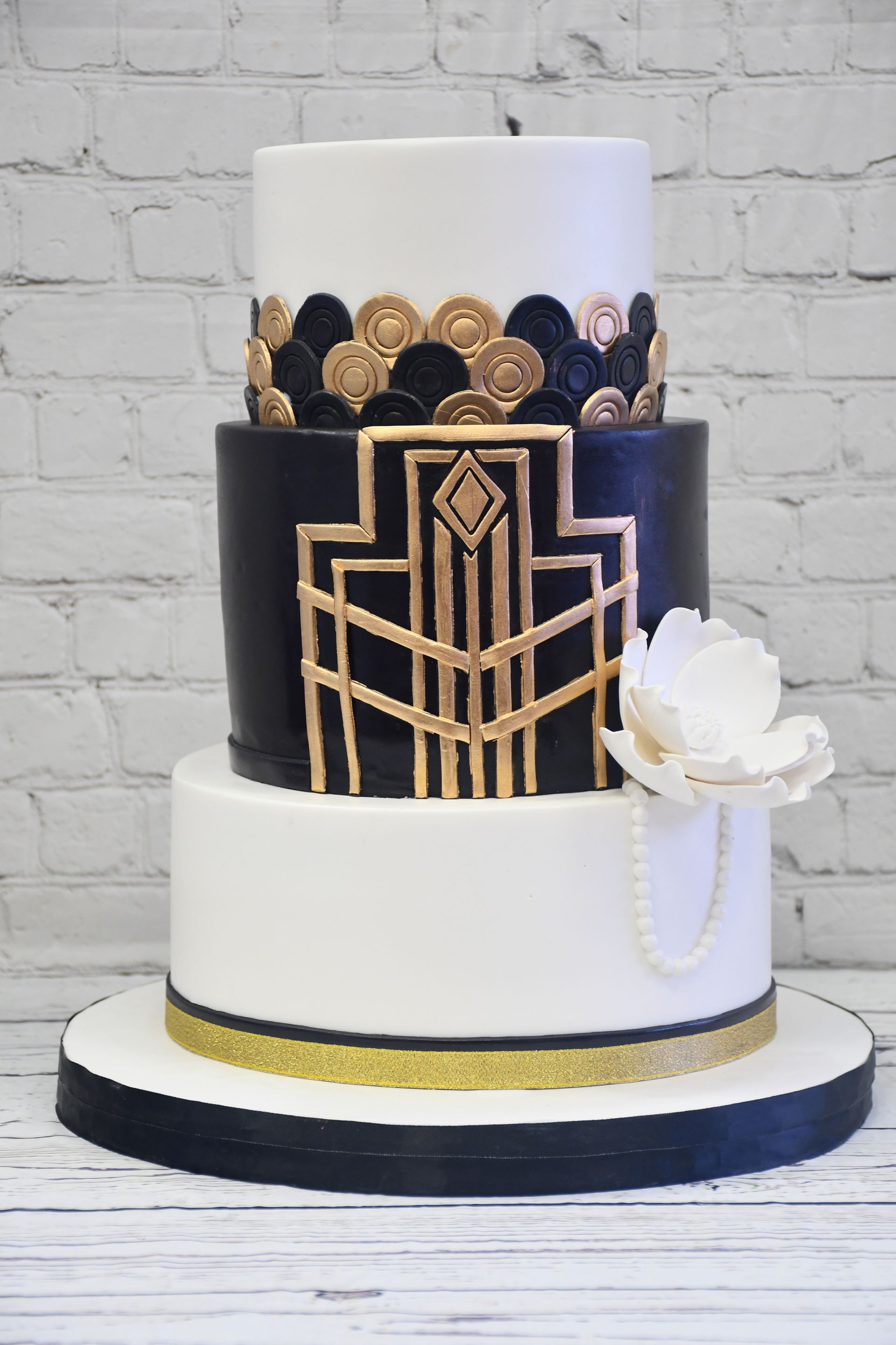 A black and white cake with a gold design on it is sitting on a table.