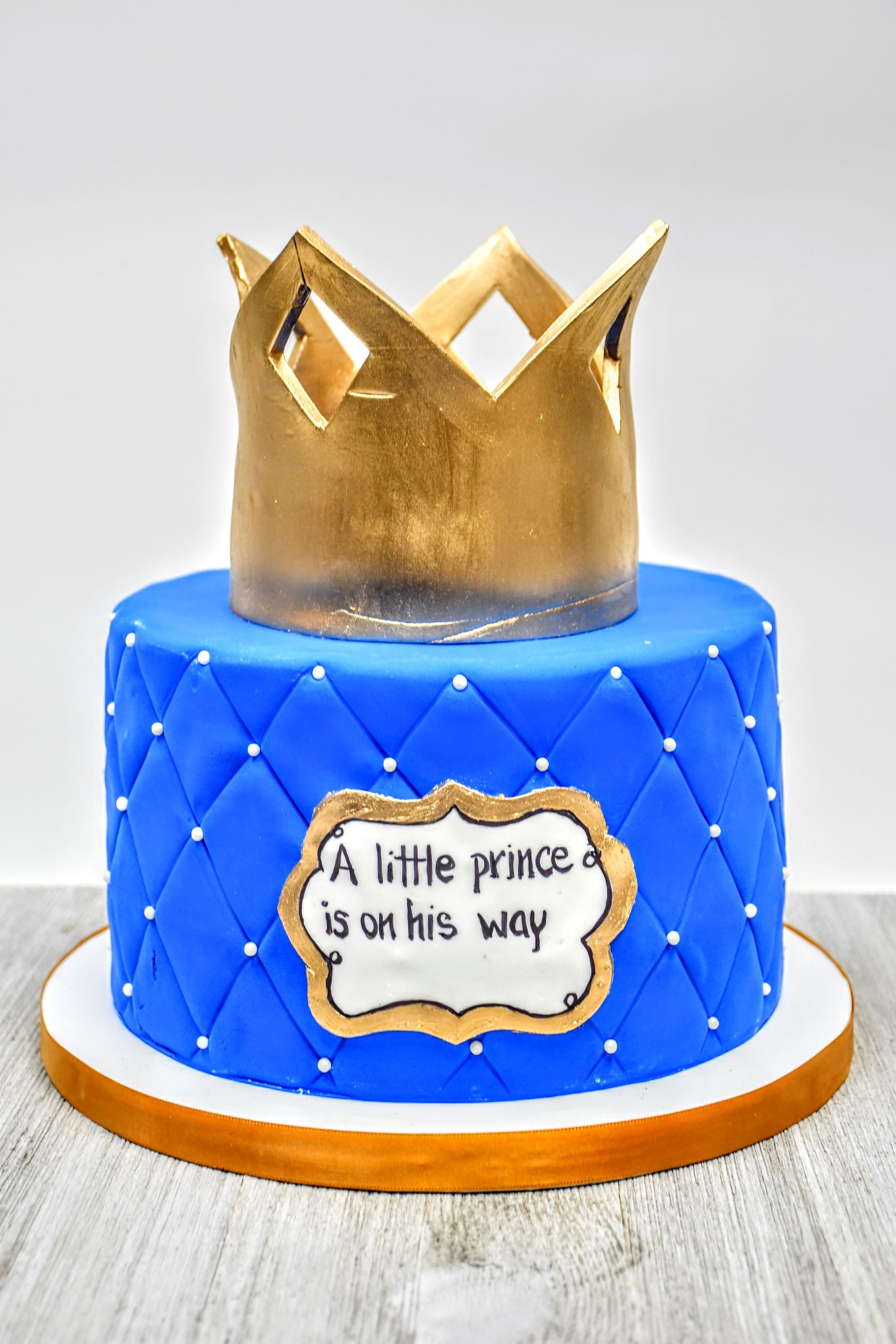 A blue cake with a gold crown on top of it
