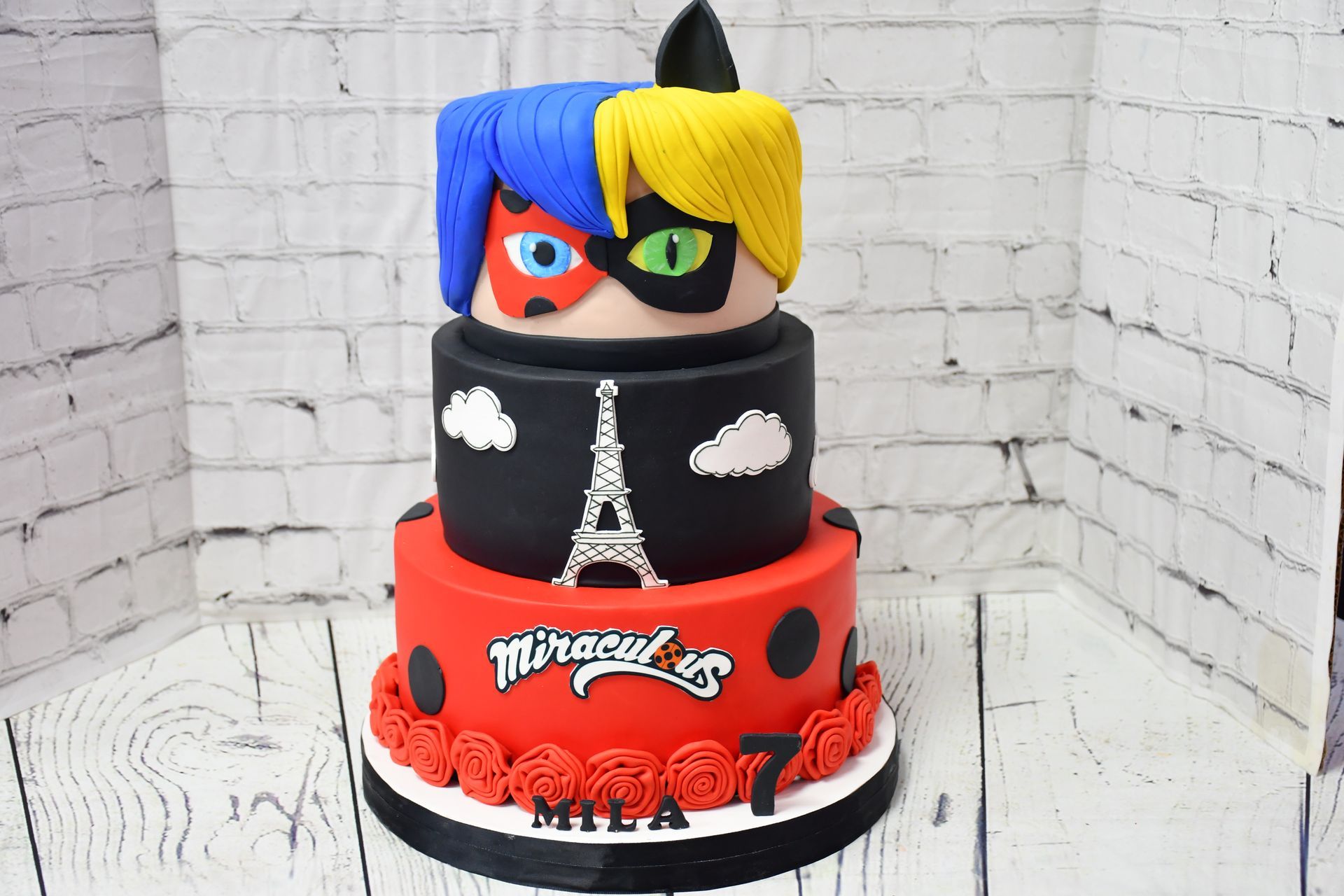 A miraculous ladybug cake is sitting on a wooden table.