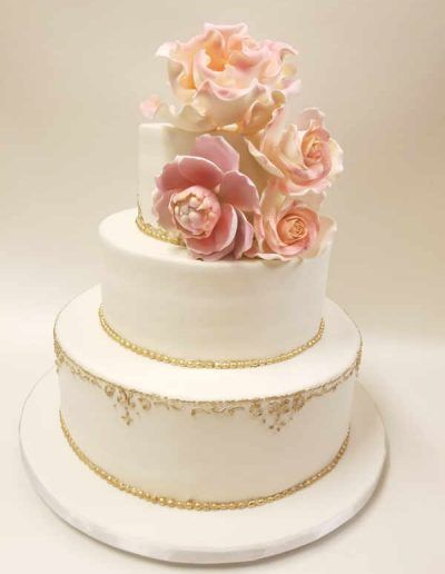 A white wedding cake with pink roses on top