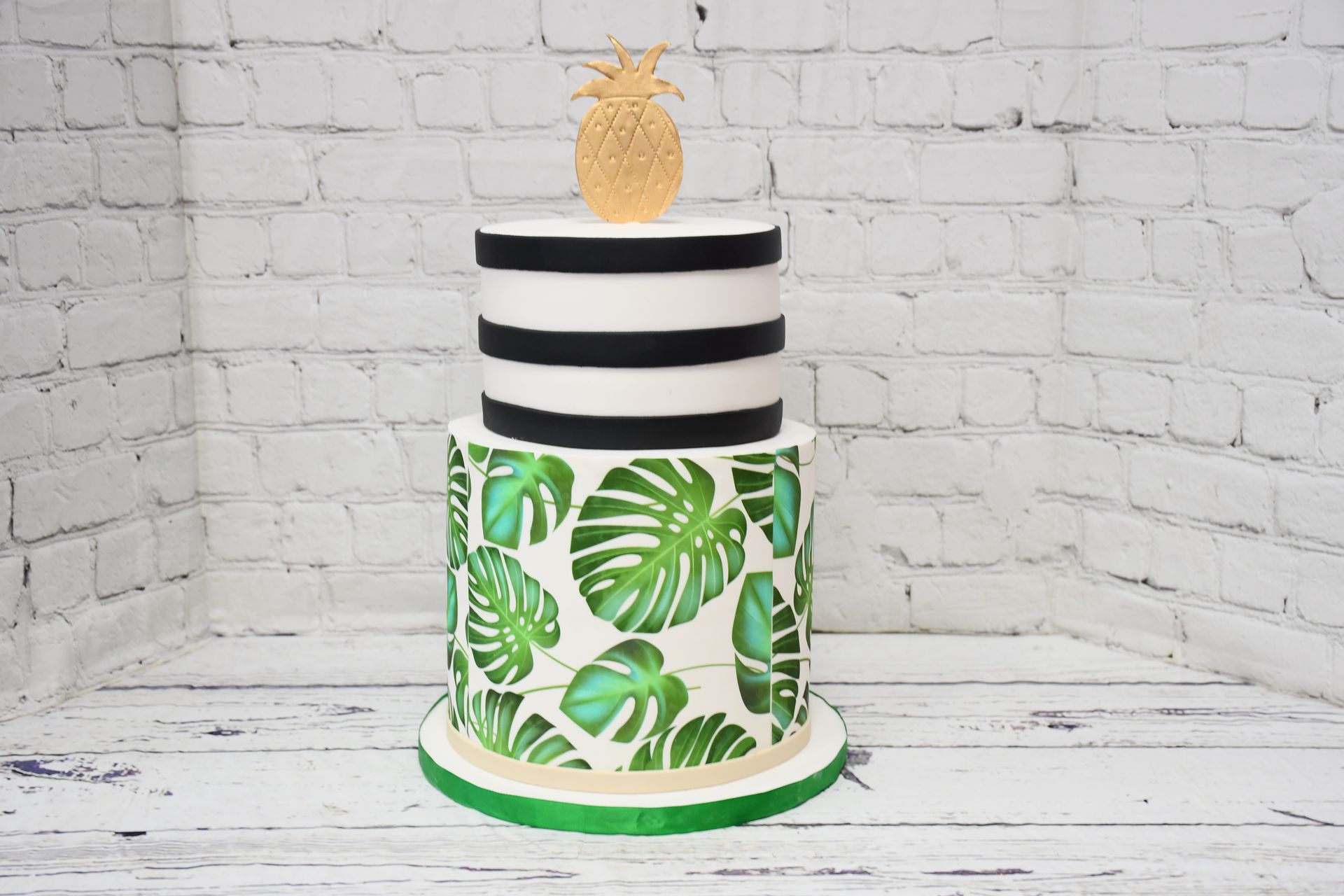 A black and white striped cake with green leaves and a pineapple on top.
