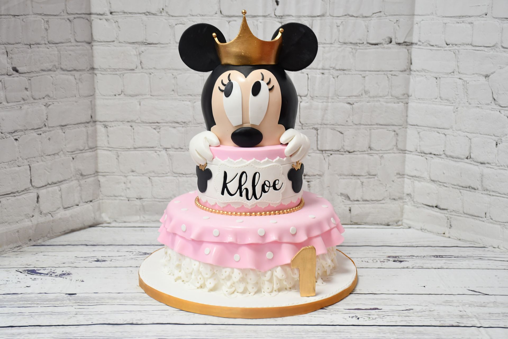 A mickey mouse cake with a crown on it is sitting on a table.