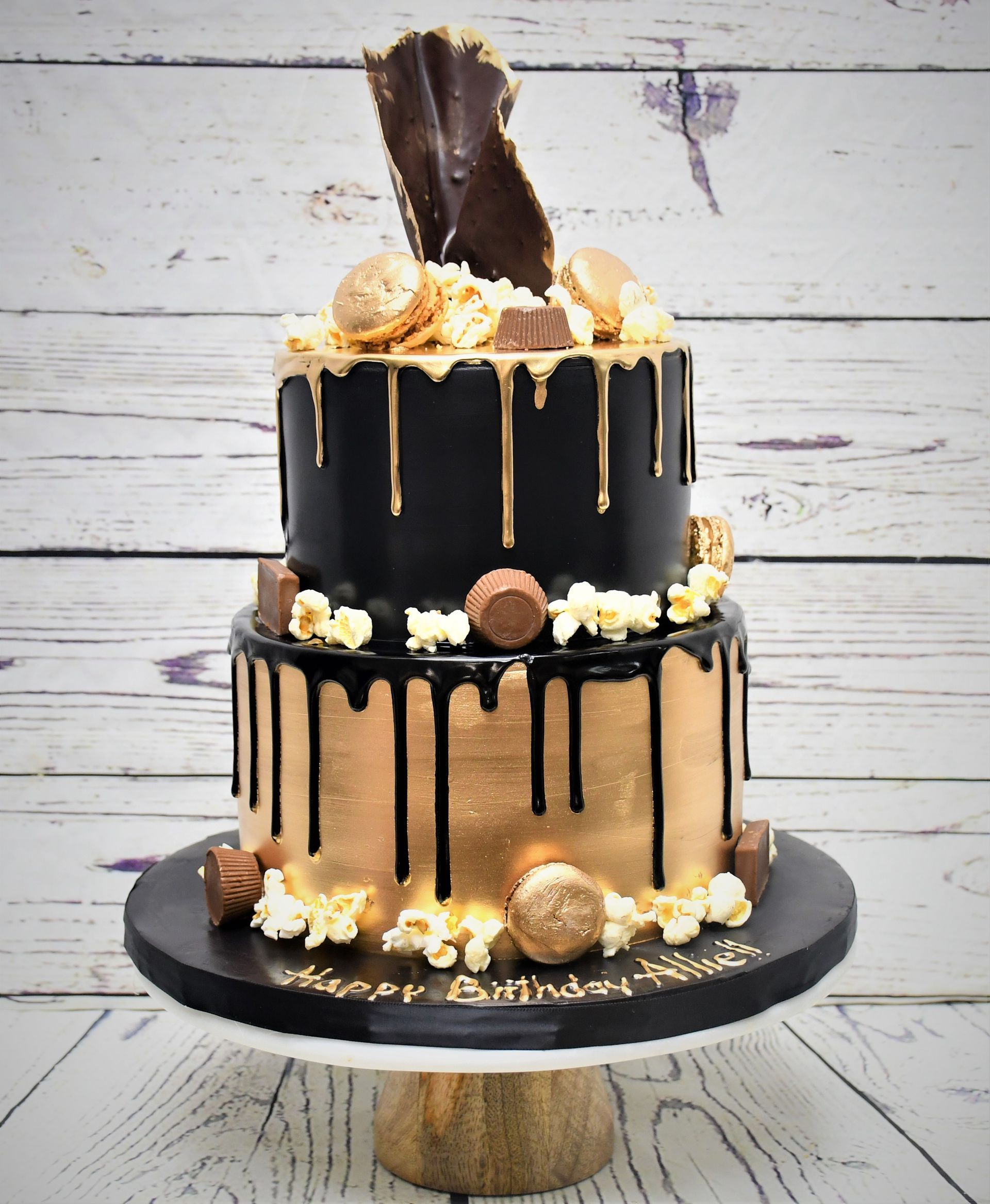 A black and gold cake on a wooden table