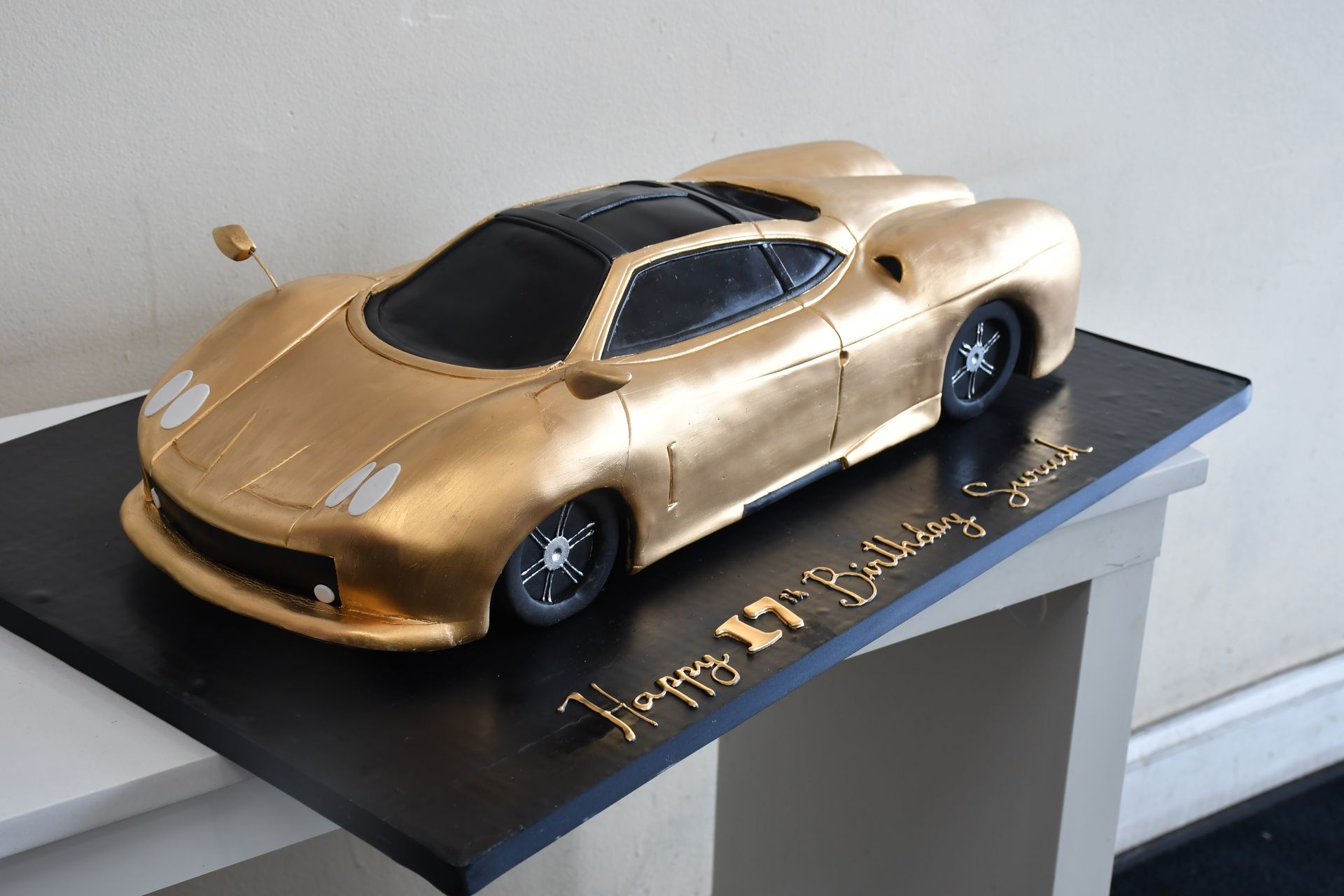 A birthday cake in the shape of a gold car