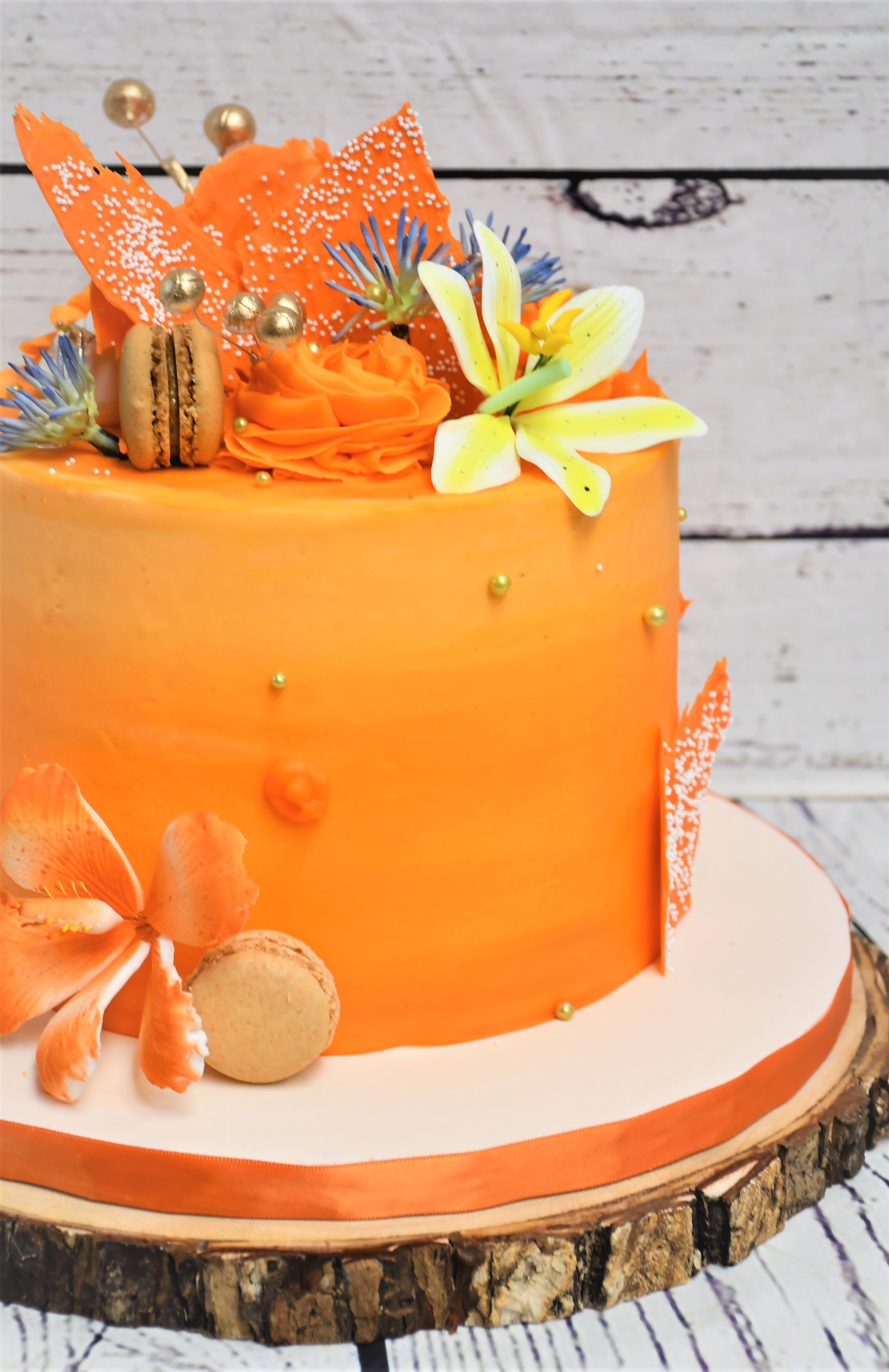 A close up of an orange cake on a wooden cutting board.