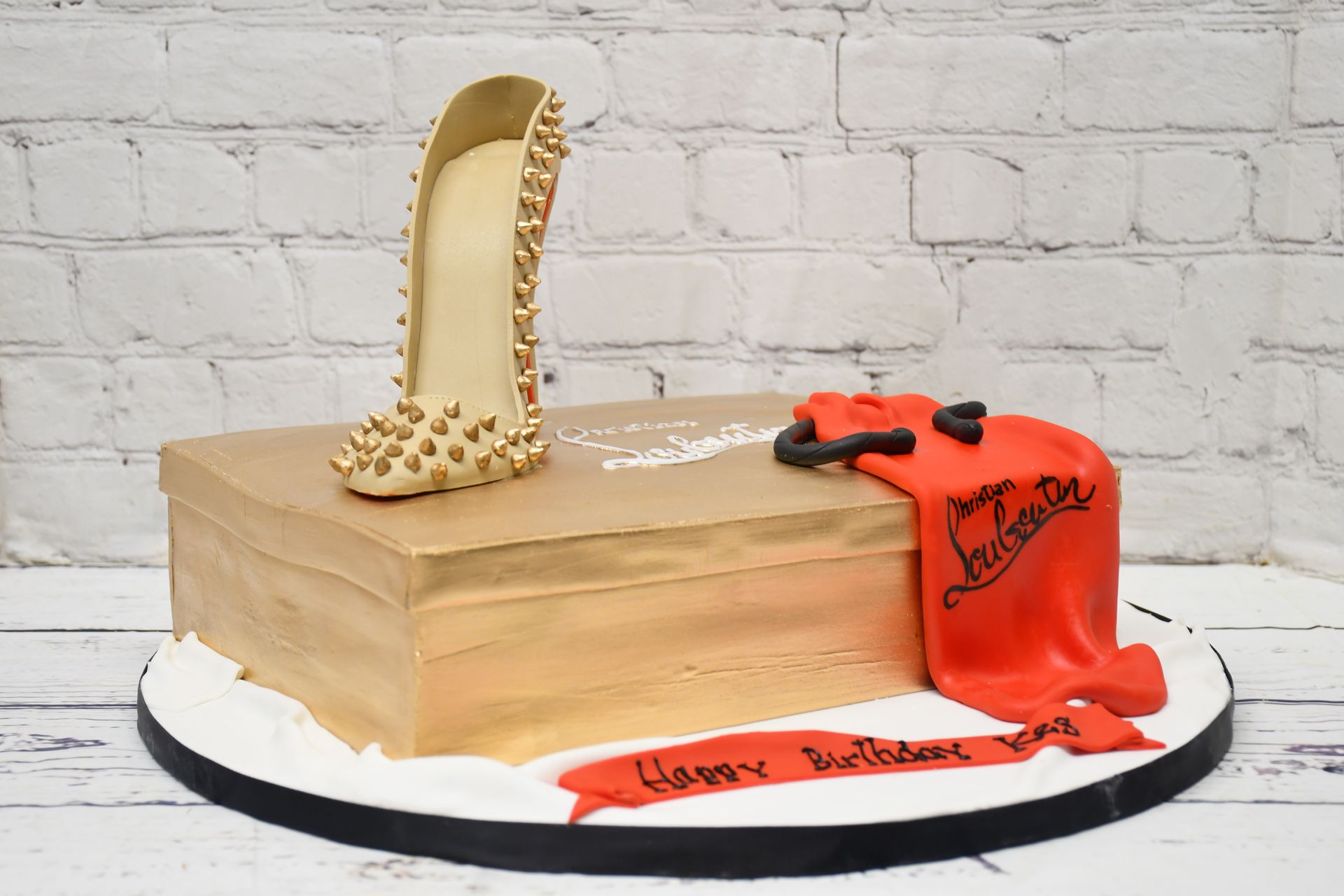 A cake with a shoe and a red cloth on it.