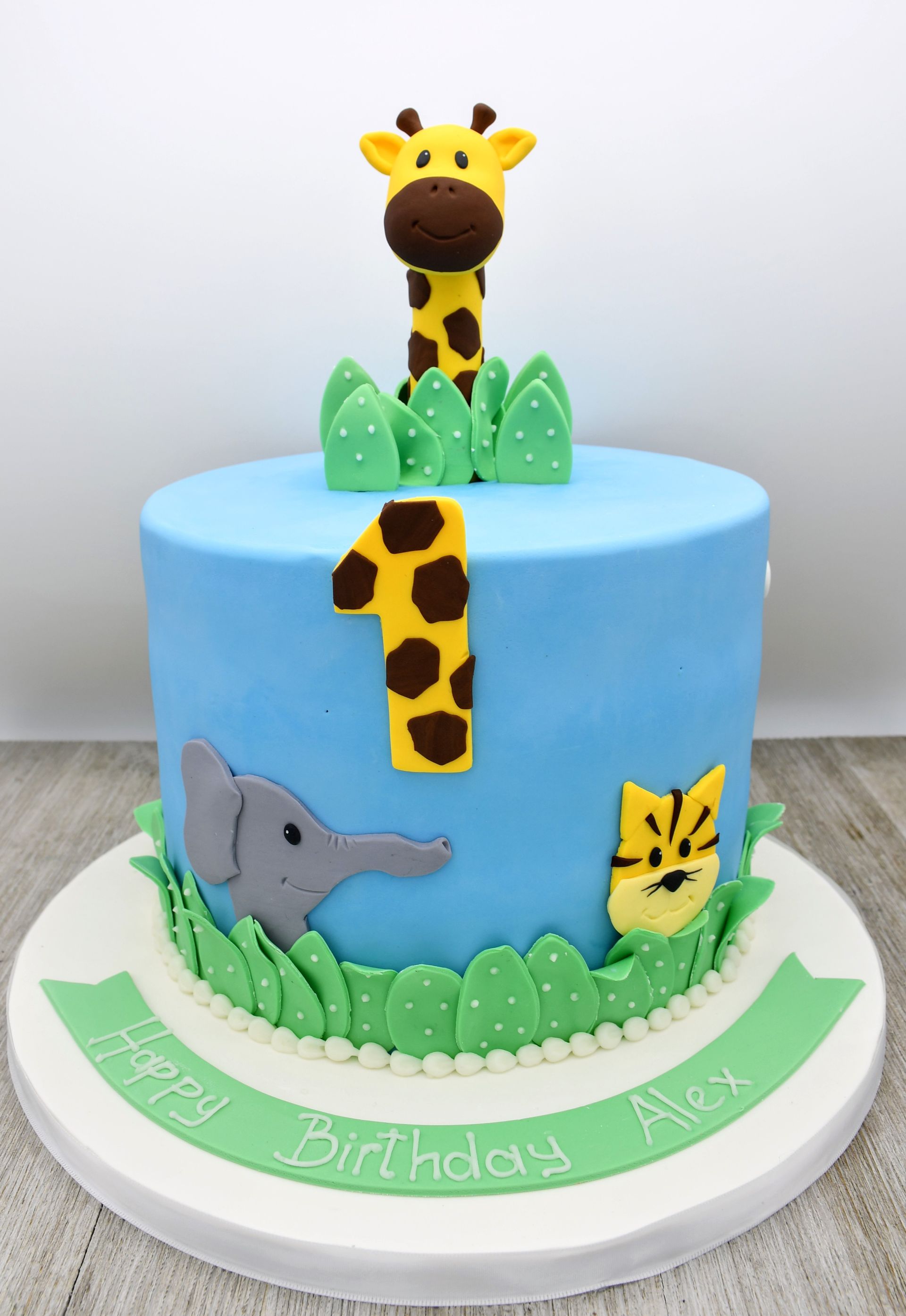 A birthday cake with a giraffe elephant and leopard on it