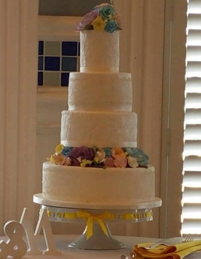 A wedding cake with flowers on top is on a table