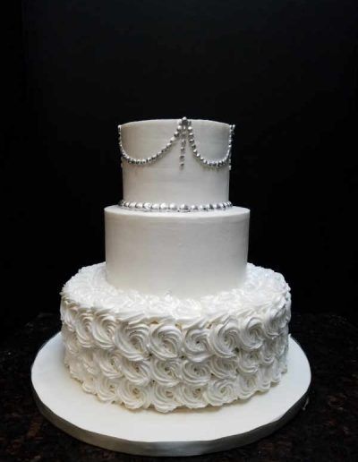 A white wedding cake with pearls on it