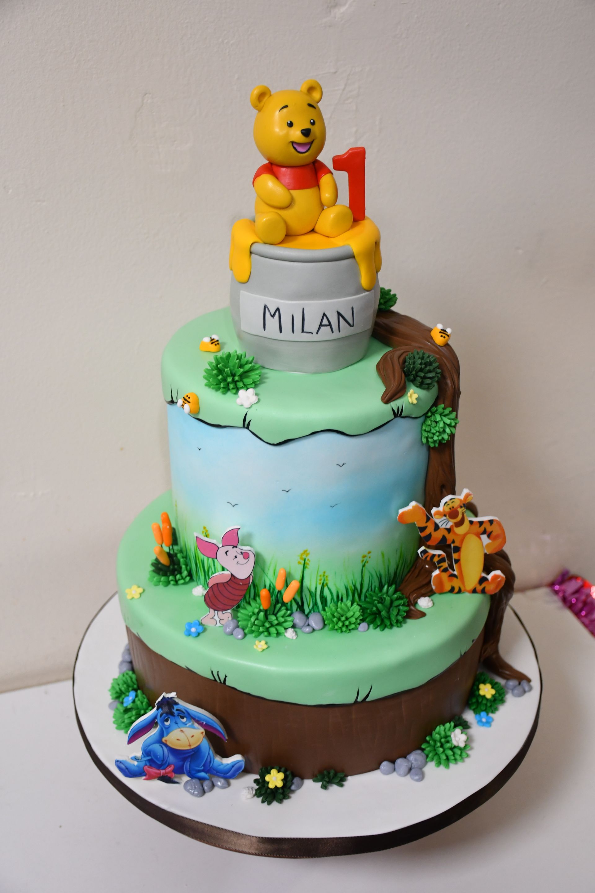A cake with winnie the pooh sitting on top of it