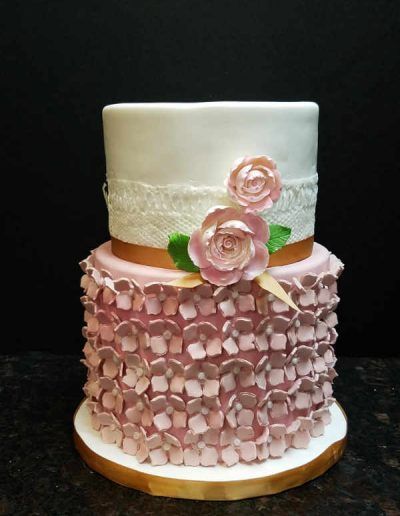 A white cake with pink ruffles and roses on top