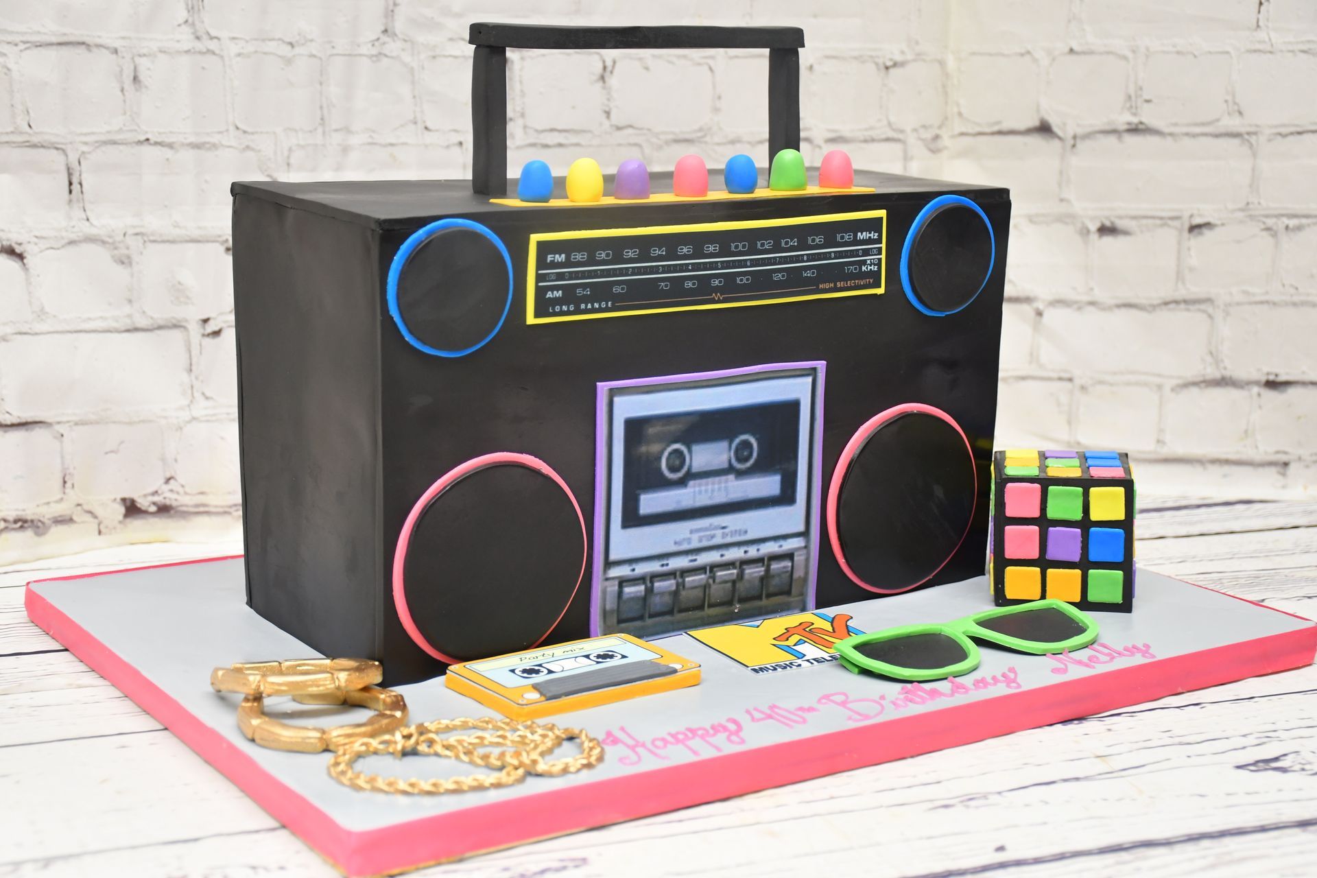 A cake in the shape of a boombox with sunglasses and a rubik 's cube.