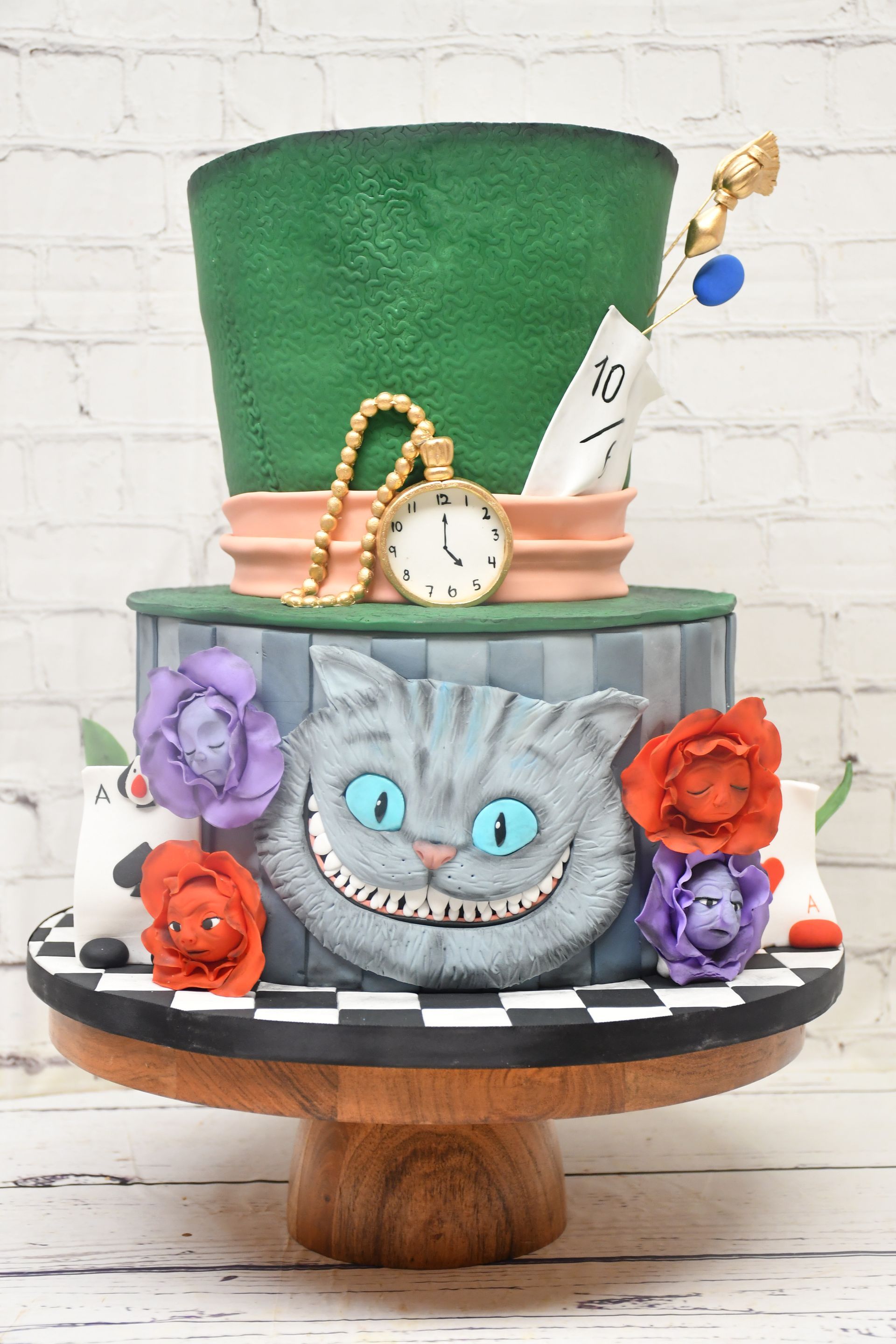 A cake that looks like a mad hatter hat with a cat on it.