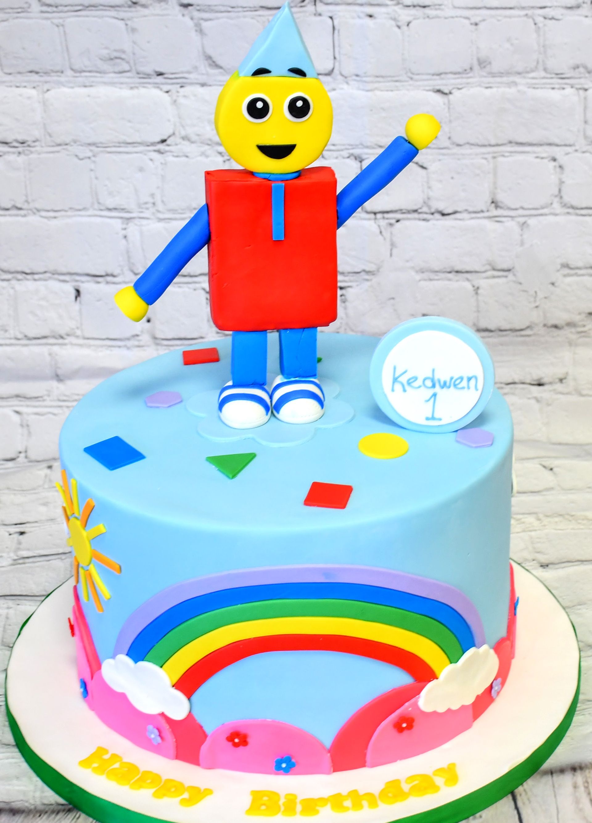 A birthday cake with a robot and a rainbow on it