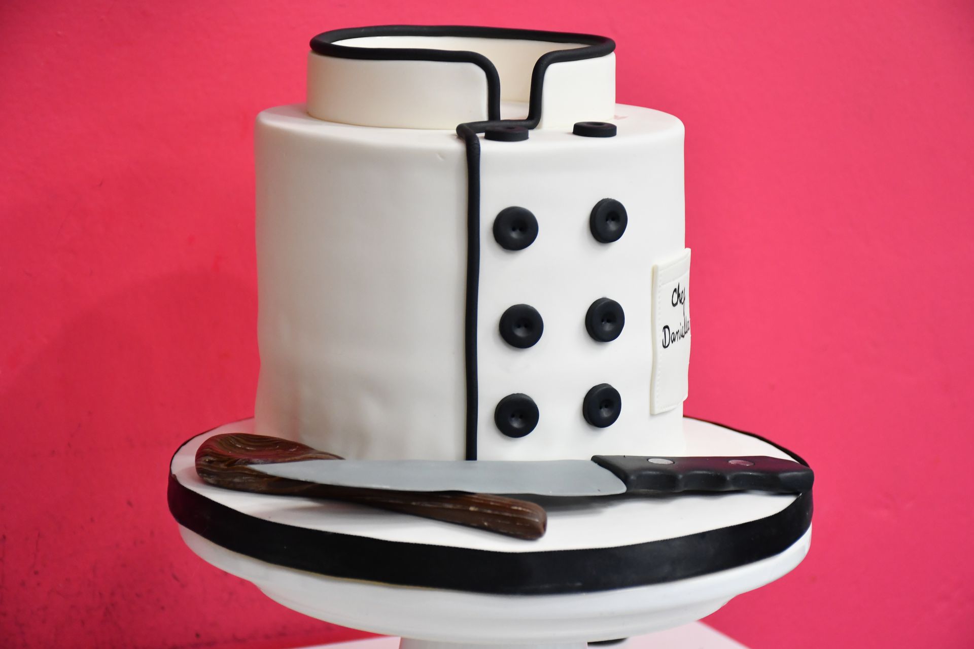 a chefs coat cake with a knife and wooden spoon
