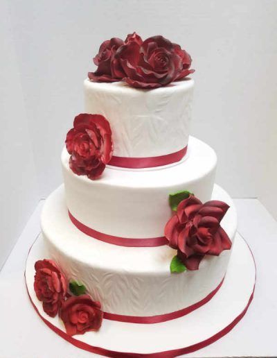 Three tiered white cake with red roses on top