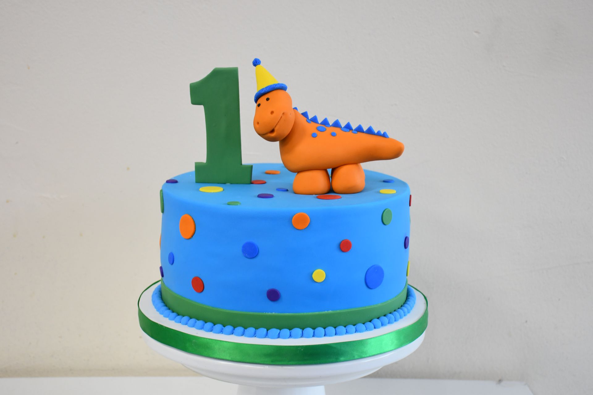 A first birthday cake with a dinosaur on top