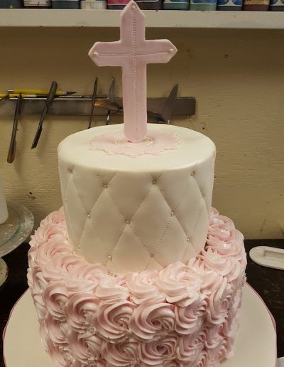A pink and white cake with a cross on top