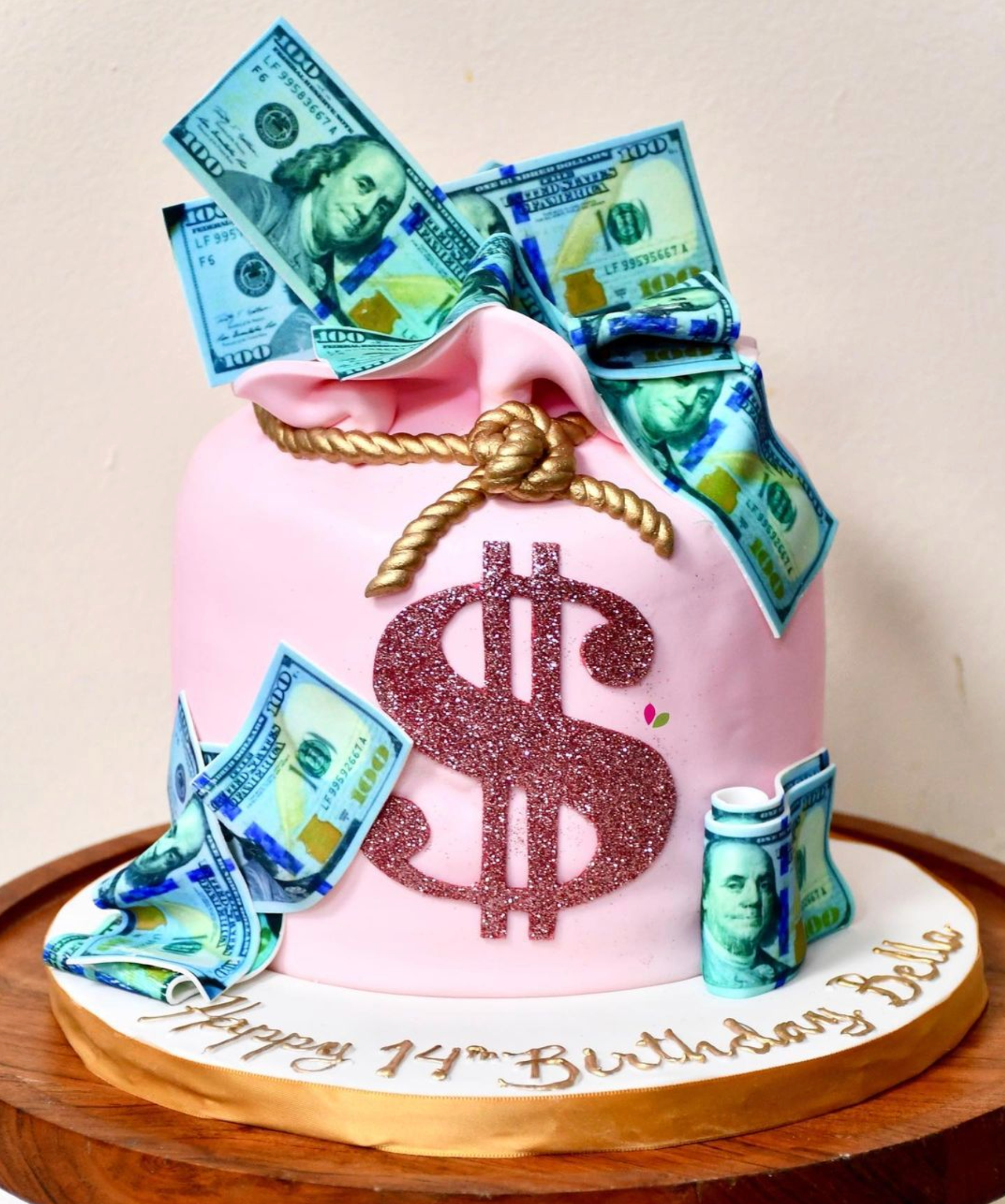A pink cake with a bag of money and a dollar sign on it