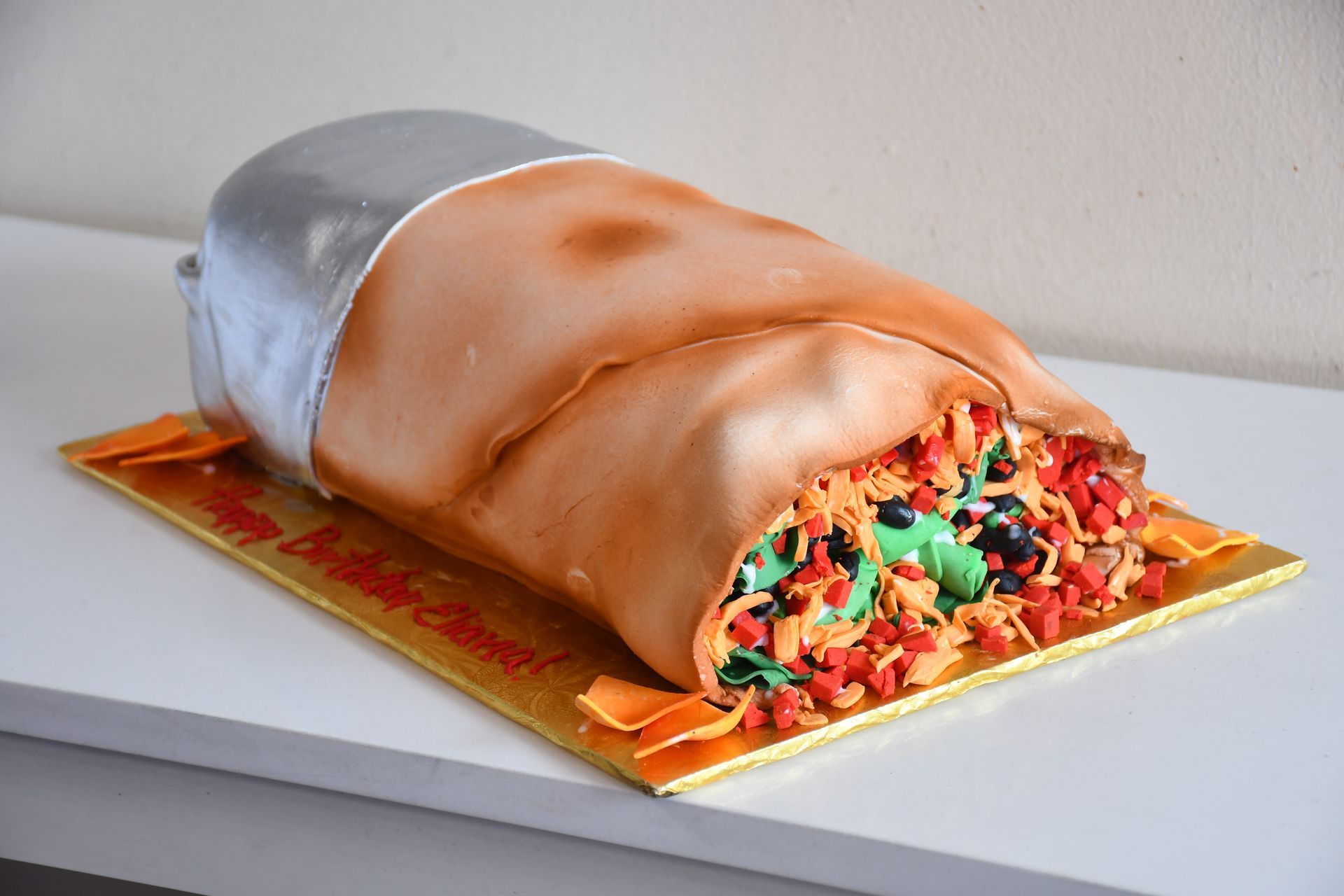 A cake that looks like a burrito is sitting on a table.