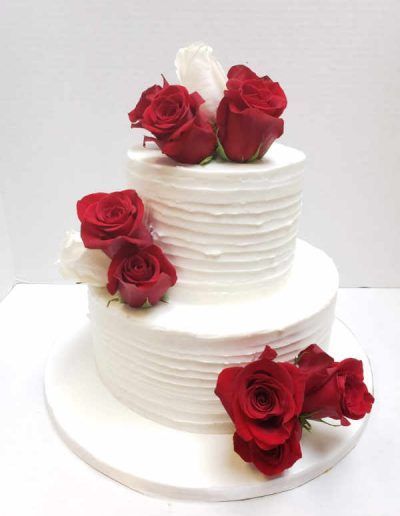 A white cake with red roses on top of it