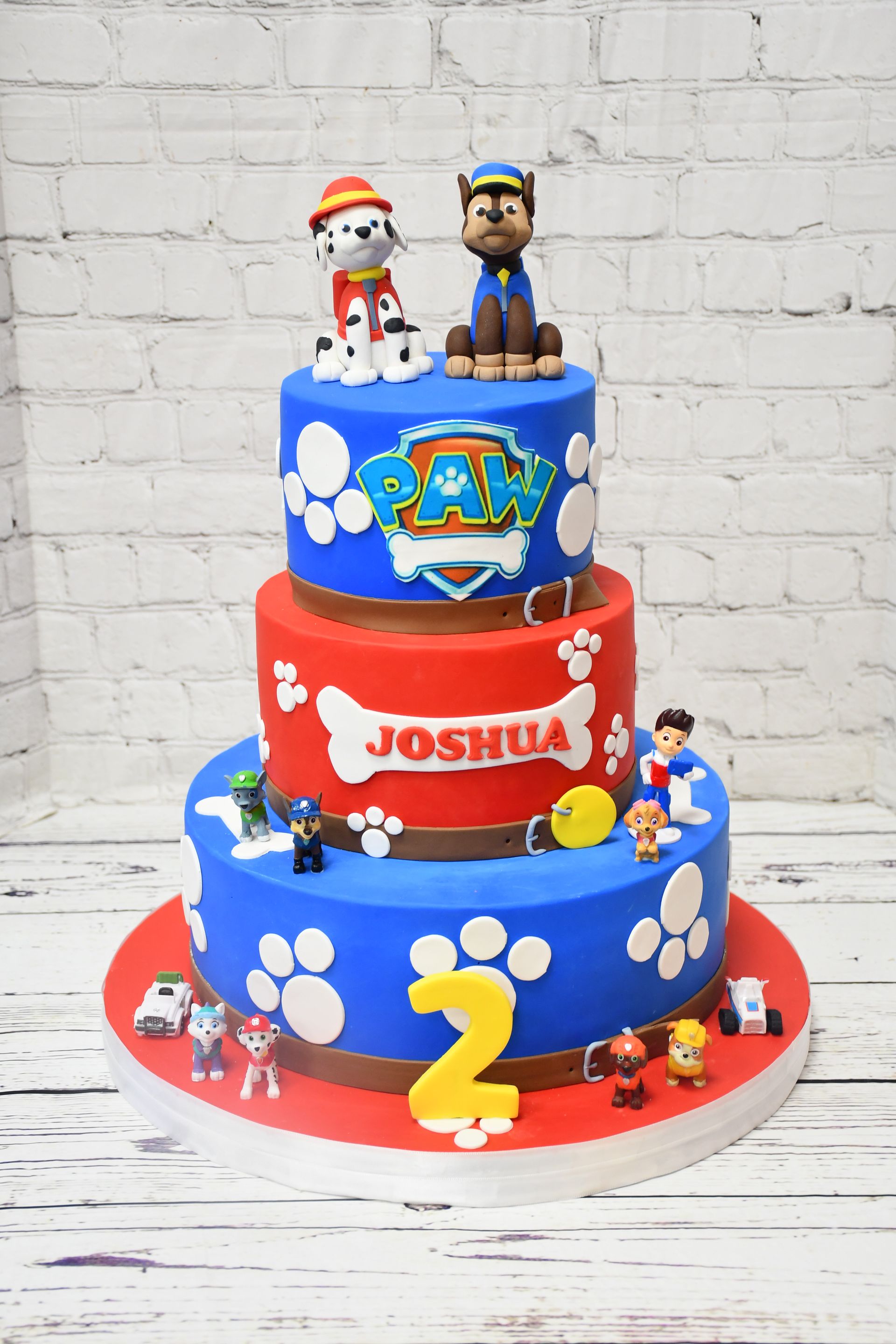 A red , blue and white cake with paw patrol characters on it