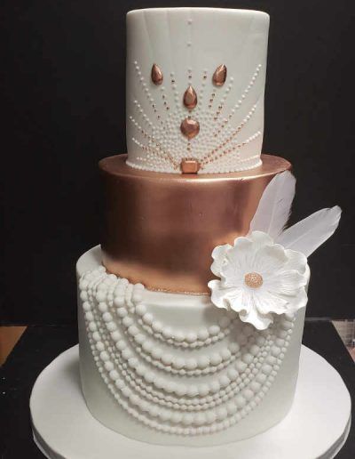 A white cake with pearls and feathers on it