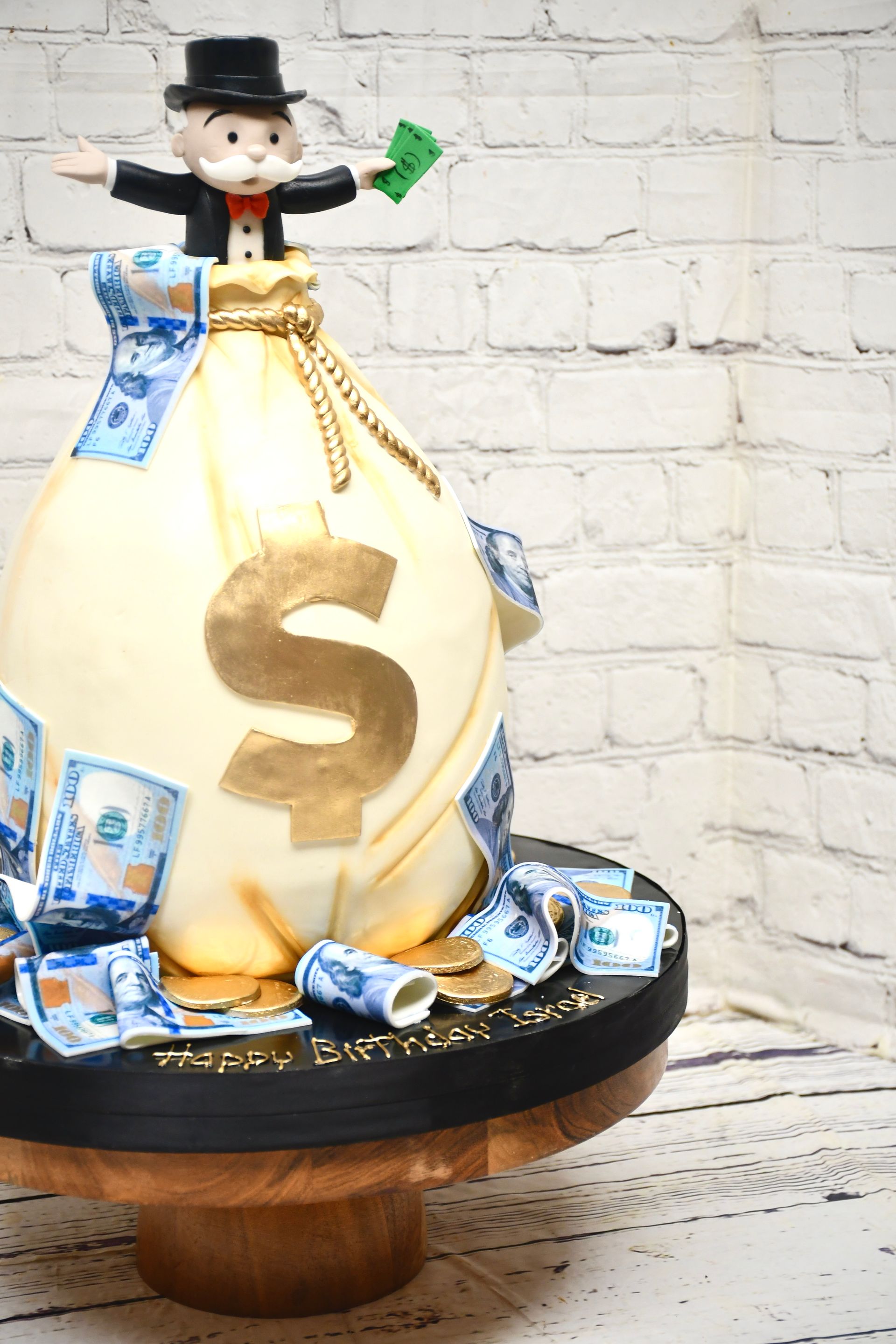 A cake with a bag of money and a man on top of it.