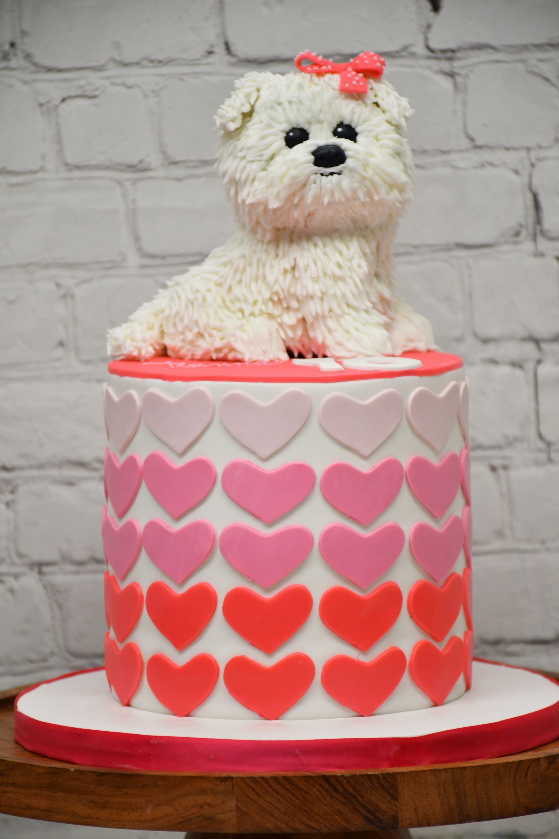 A white dog is sitting on top of a cake with hearts on it