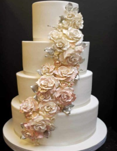 A white wedding cake with pink and white roses on it.