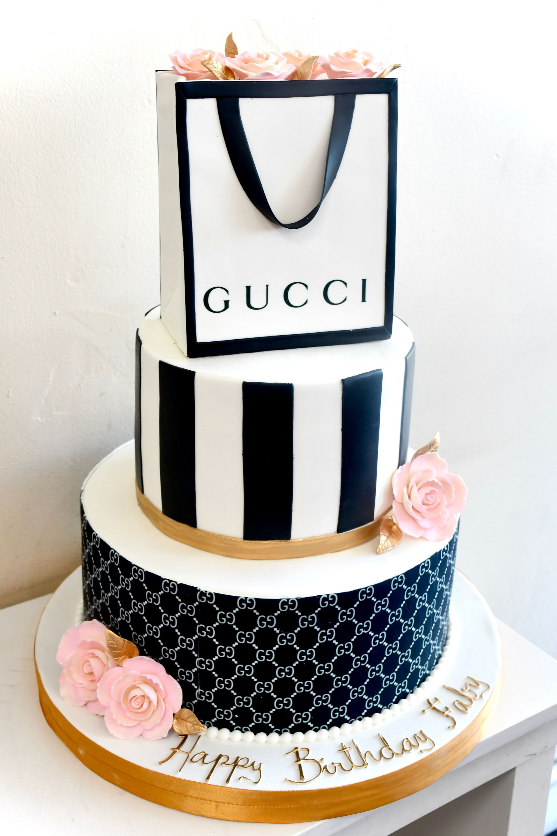 A black and white cake with a gucci bag on top