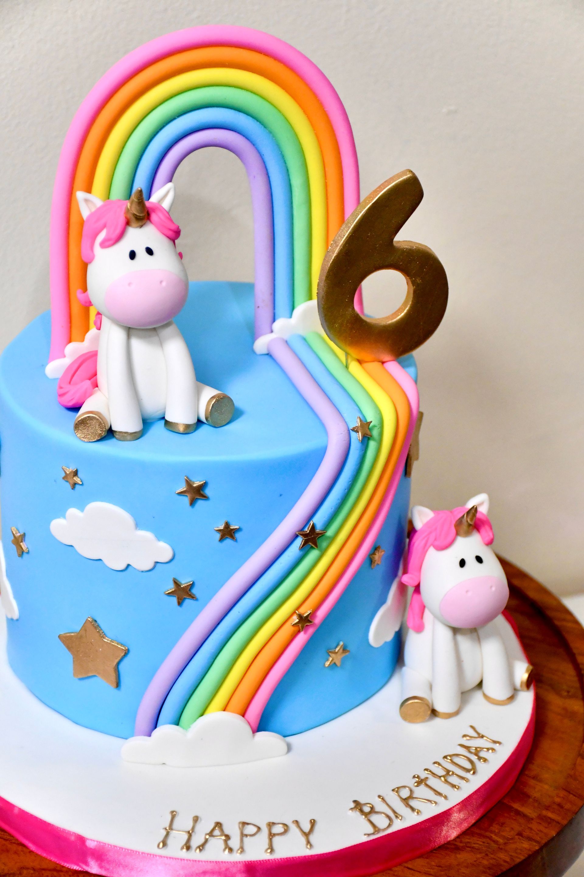 A birthday cake with two unicorns and a rainbow on it
