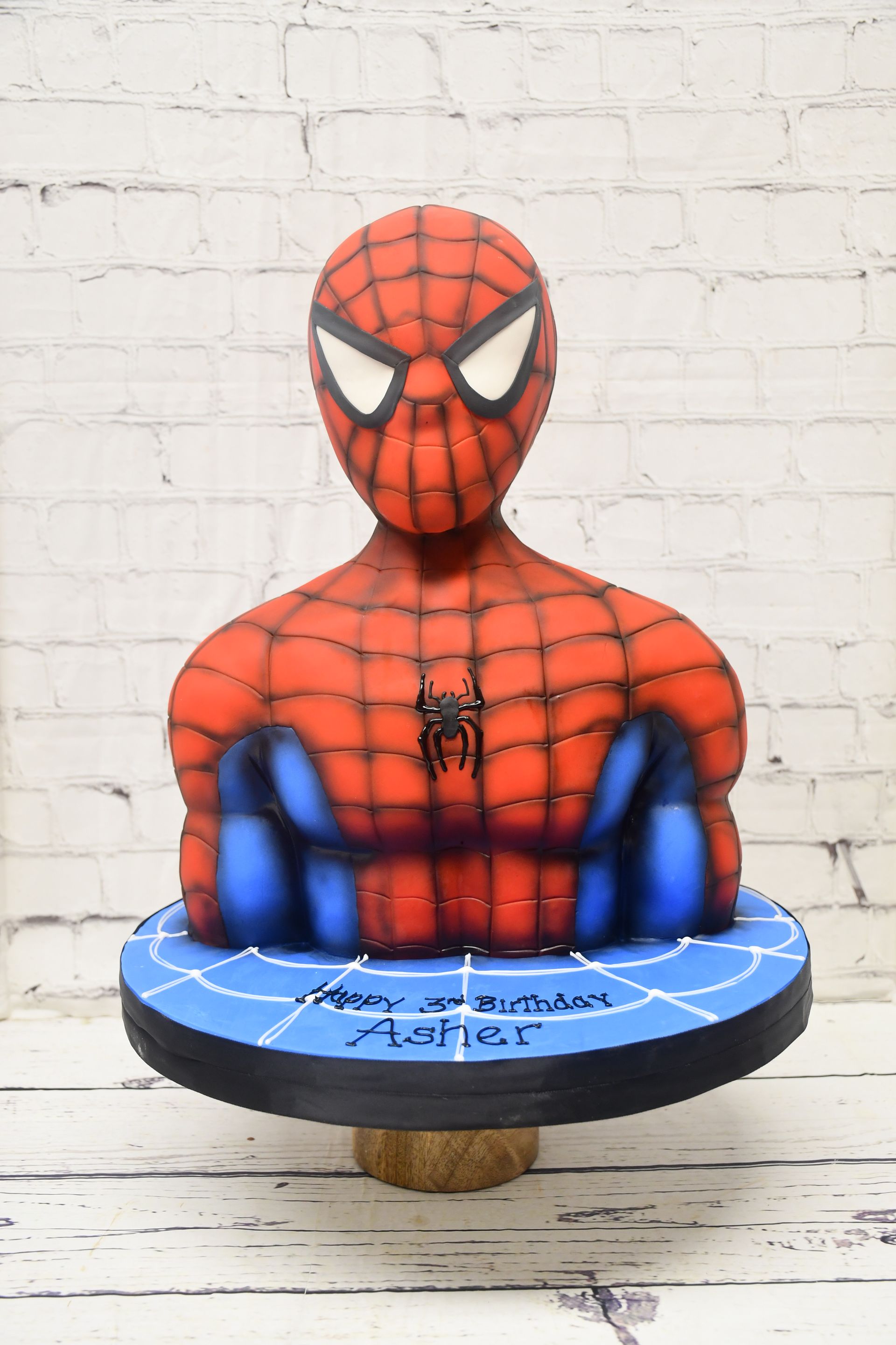A spiderman cake topper is sitting on a wooden table.