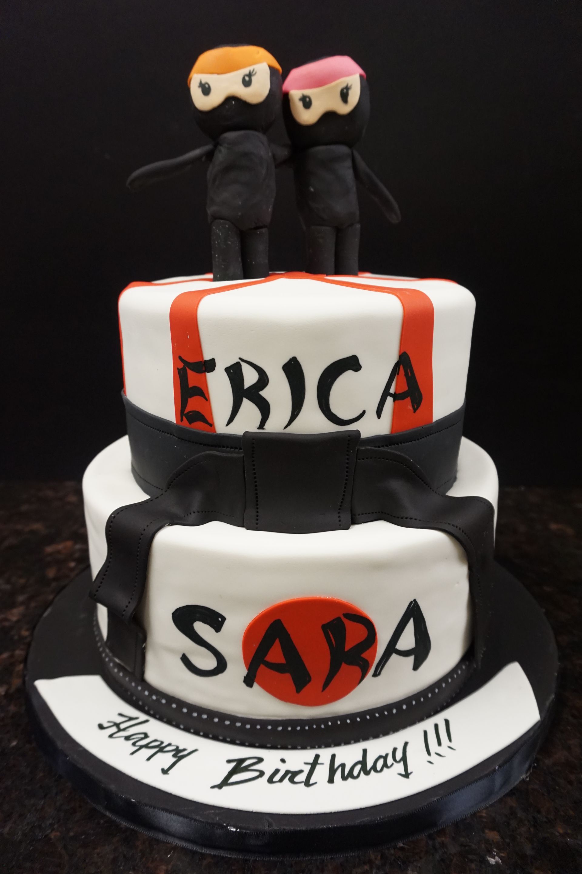 A birthday cake for sara with two ninjas on top