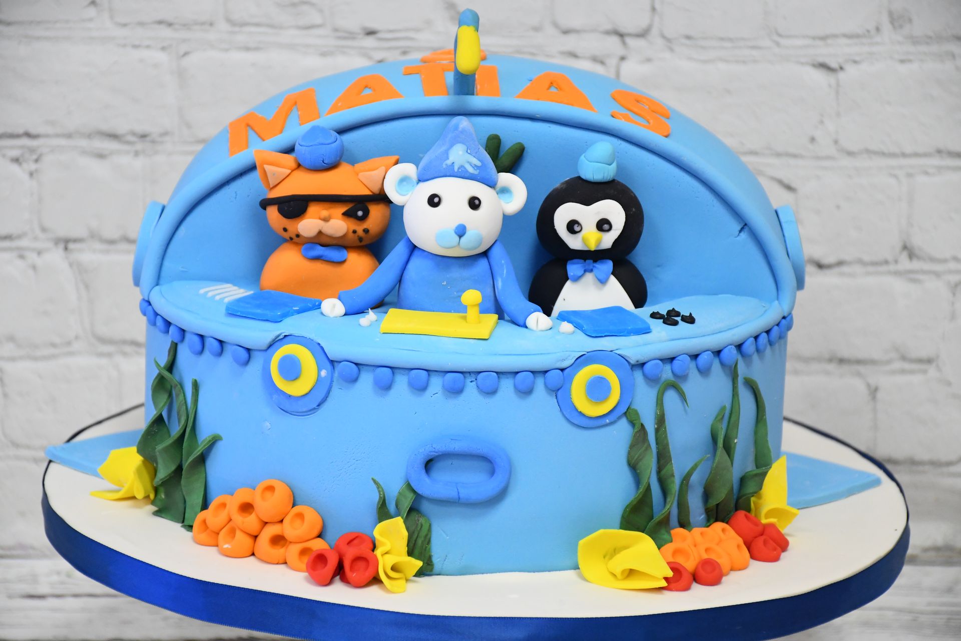 A blue cake with a cat penguin and bear on it